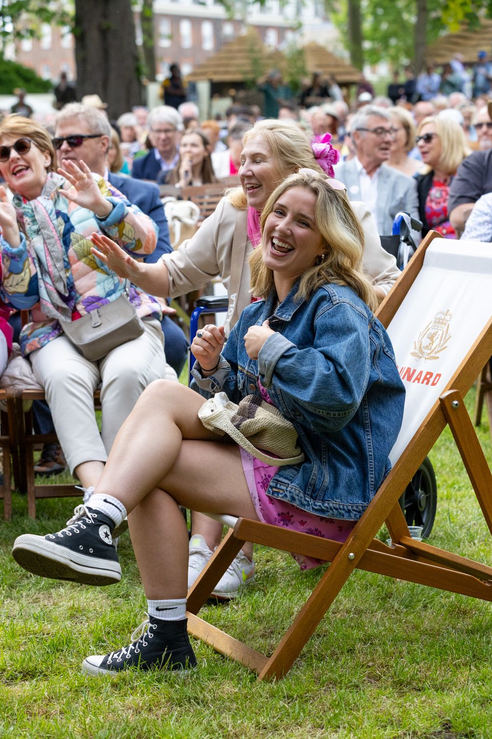 Festive outdoor event with people enjoying themselves in lawn chairs while wearing casual summer attire and denim.