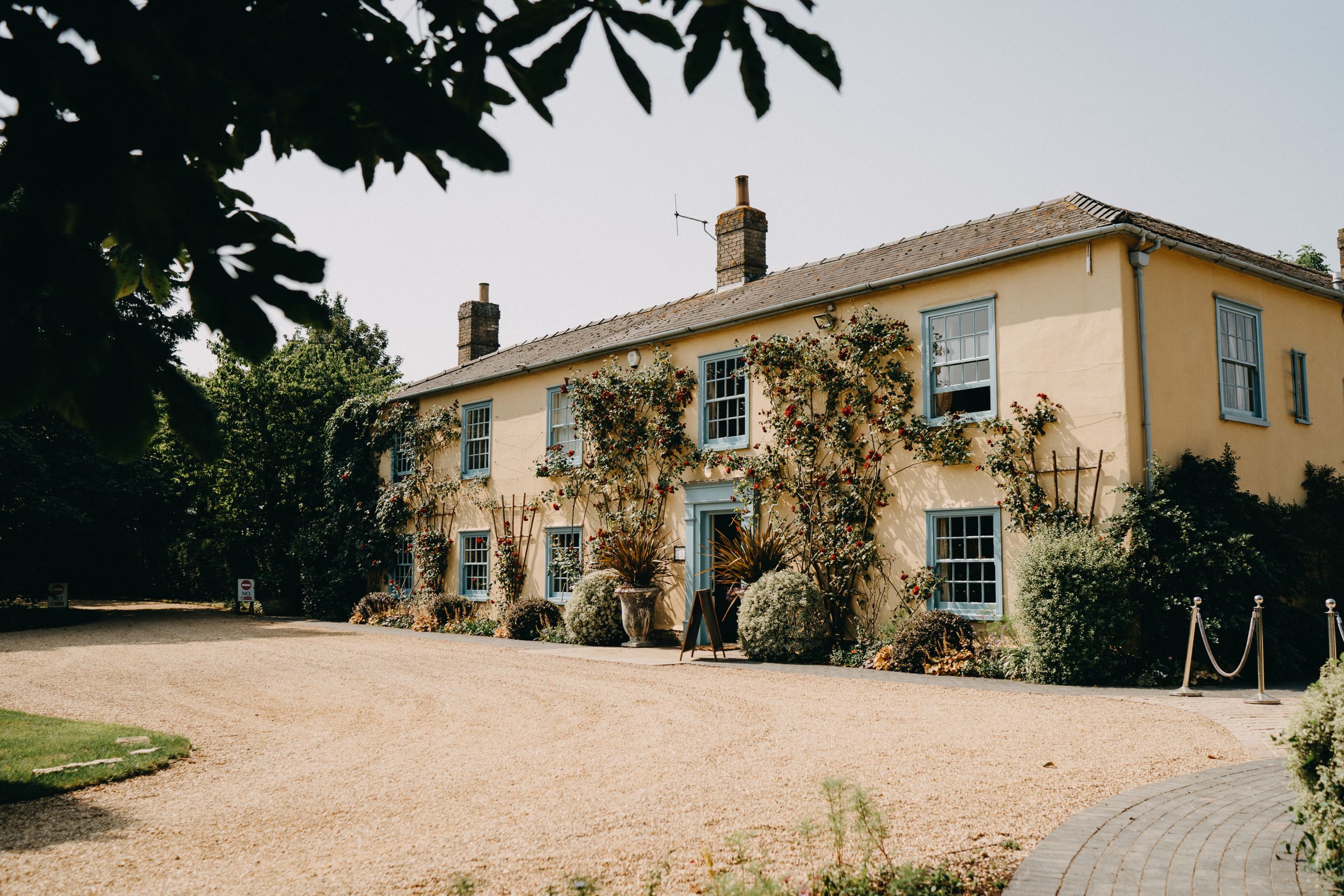 Yellow country house at South Farm with climbing vines and gravel driveway.