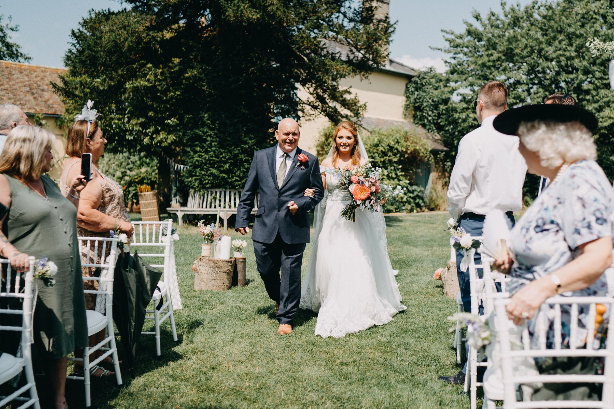 An outdoor garden wedding ceremony at South Farm with white chairs and floral decorations.