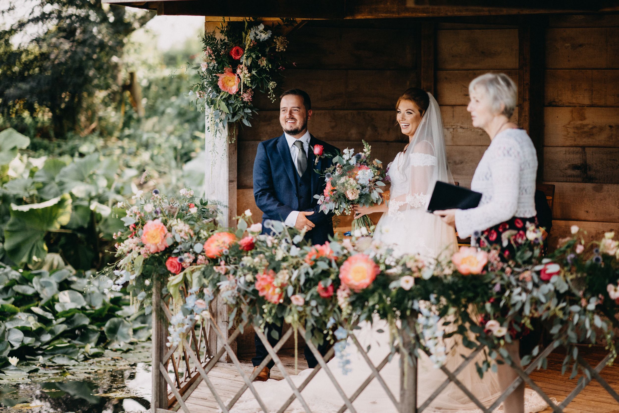 Wedding ceremony in South Farm rustic wooden gazebo decorated with pink and peach florals.