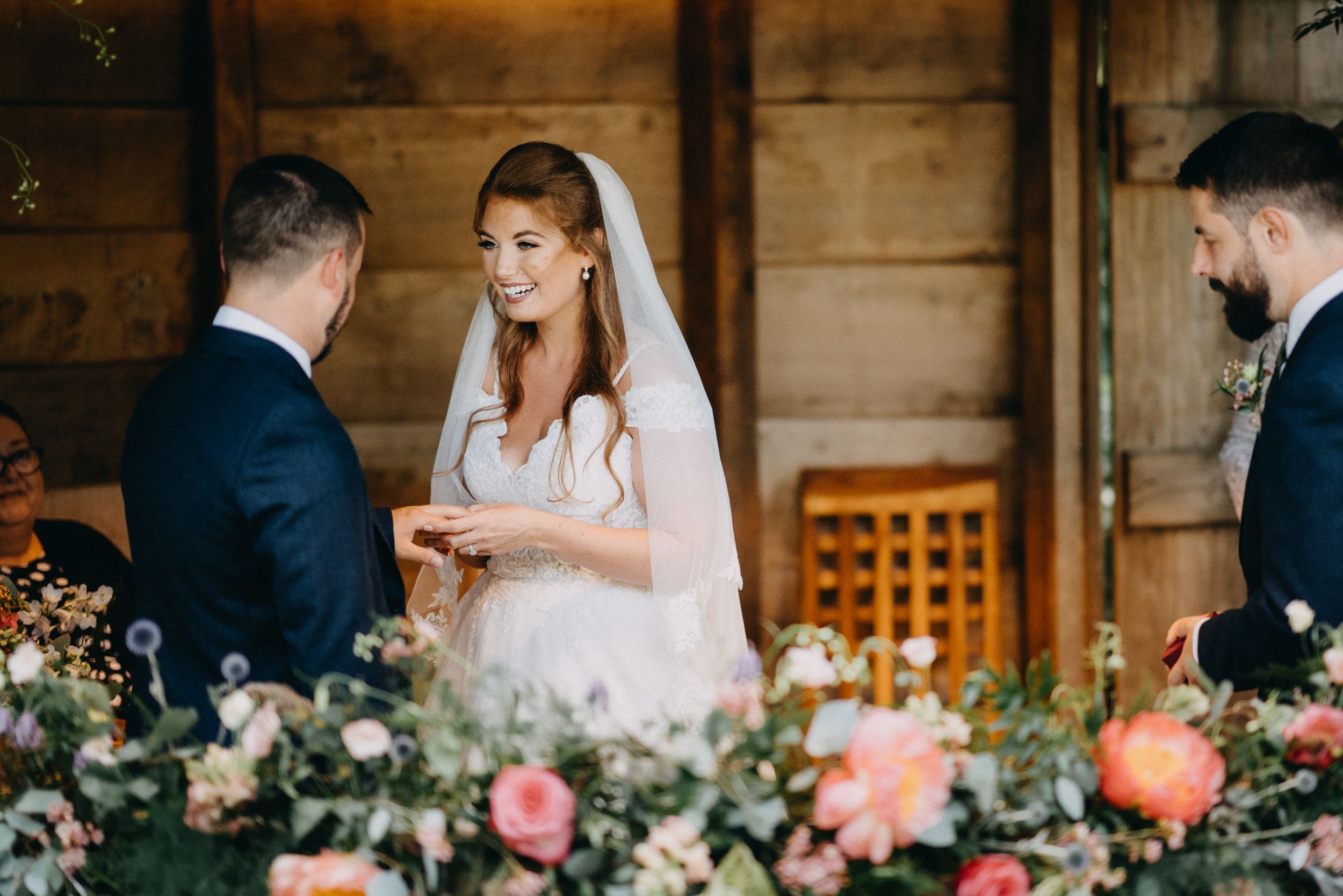 Intimate wedding ceremony moment in a rustic wooden venue with floral decorations.