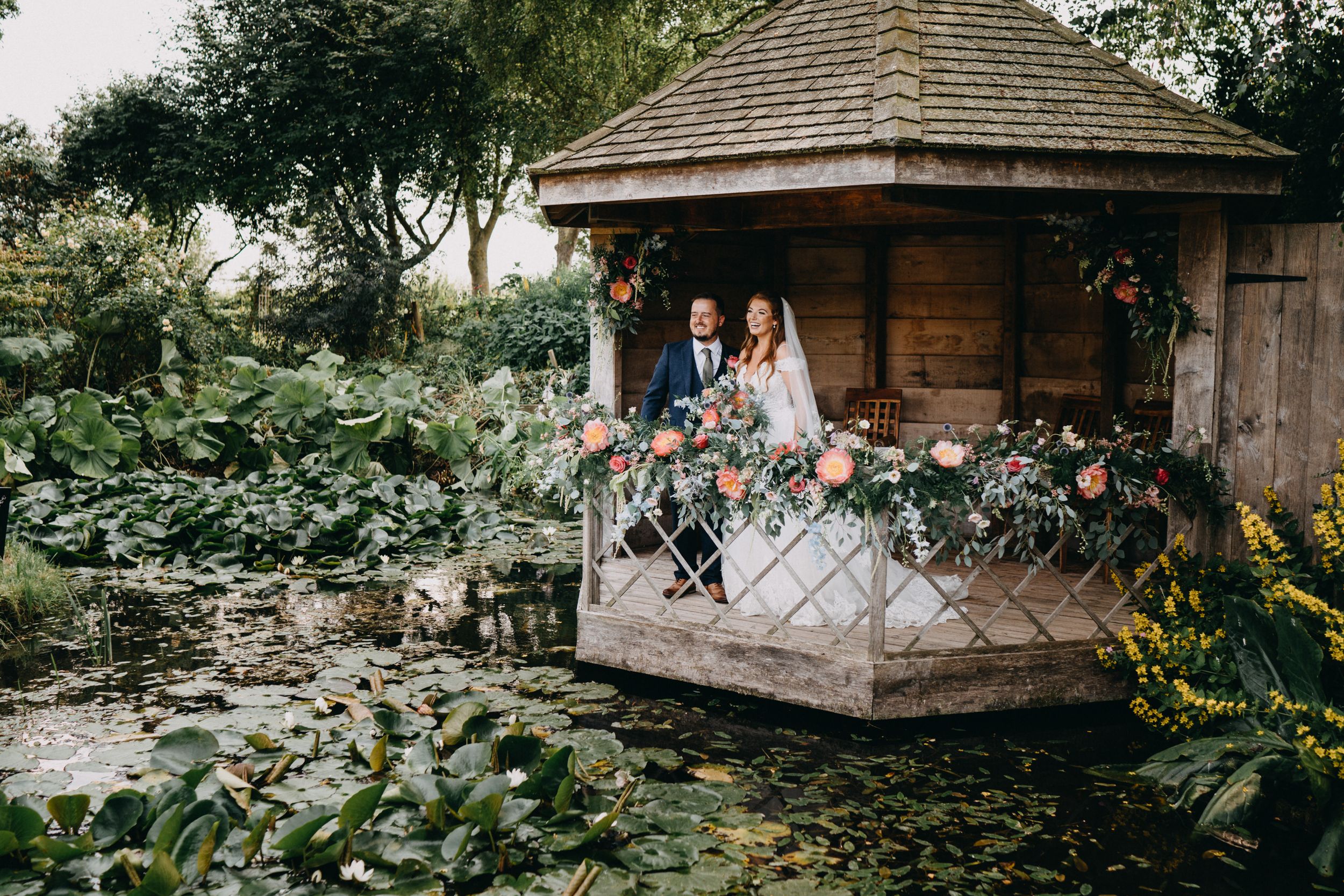 Wedding couple in a rustic wooden gazebo surrounded by lush garden foliage of South Farm.
