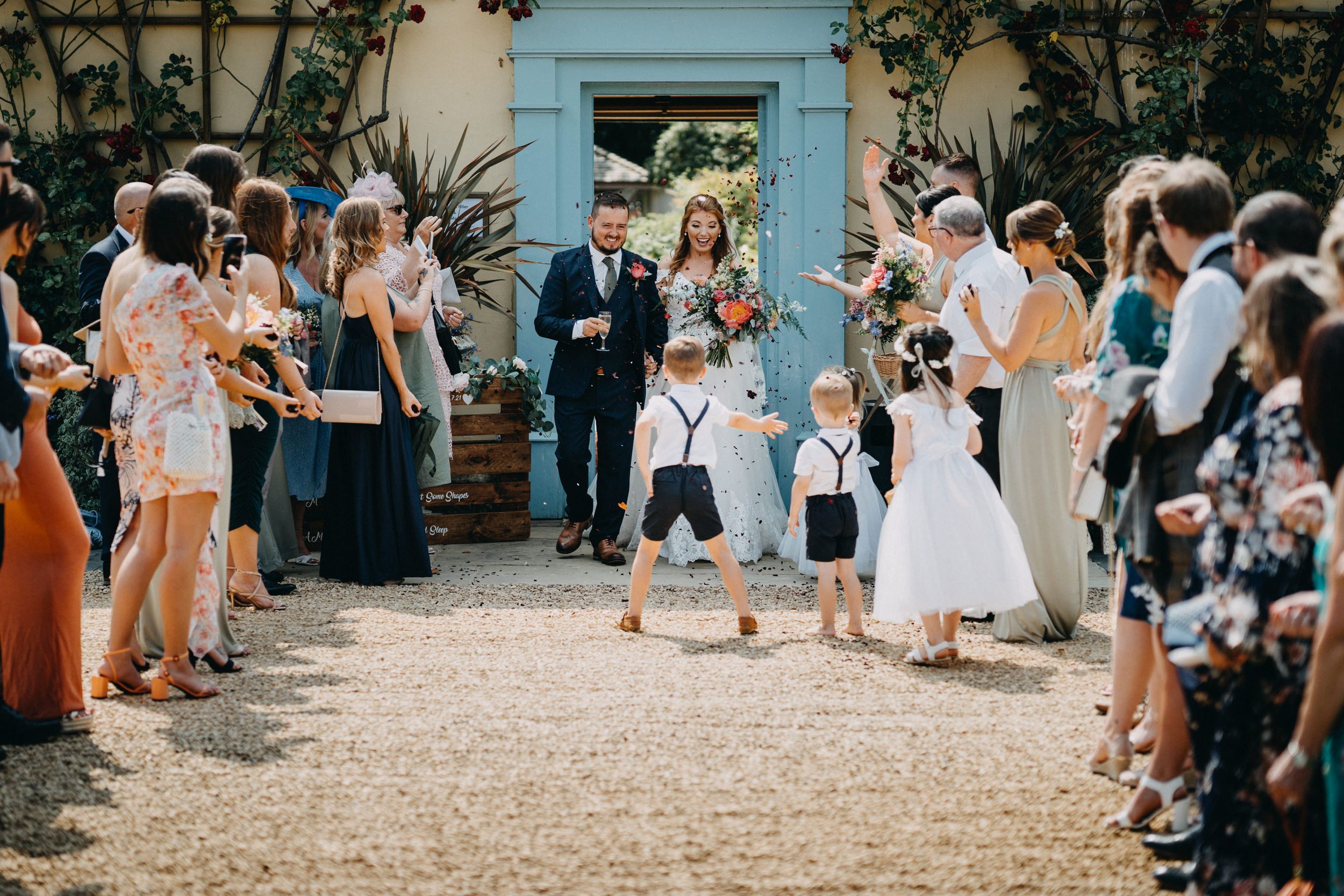 Wedding guests line a path throwing confetti during the ceremony exit.