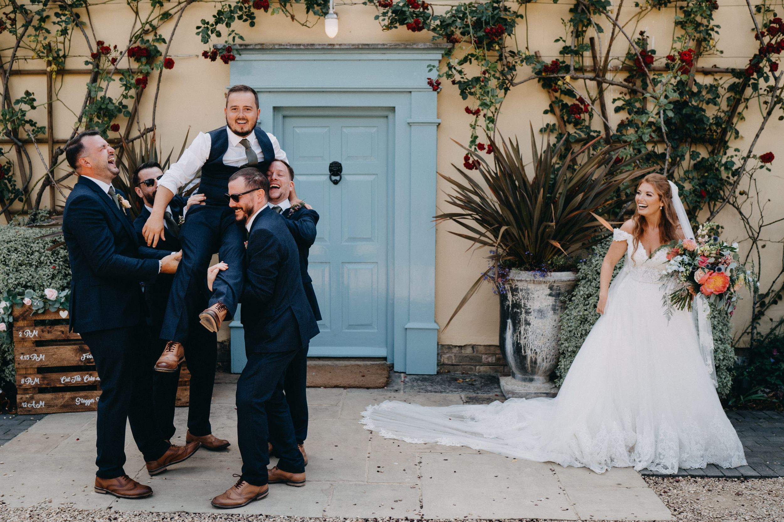 Playful wedding party moment outside a blue door with climbing vines.