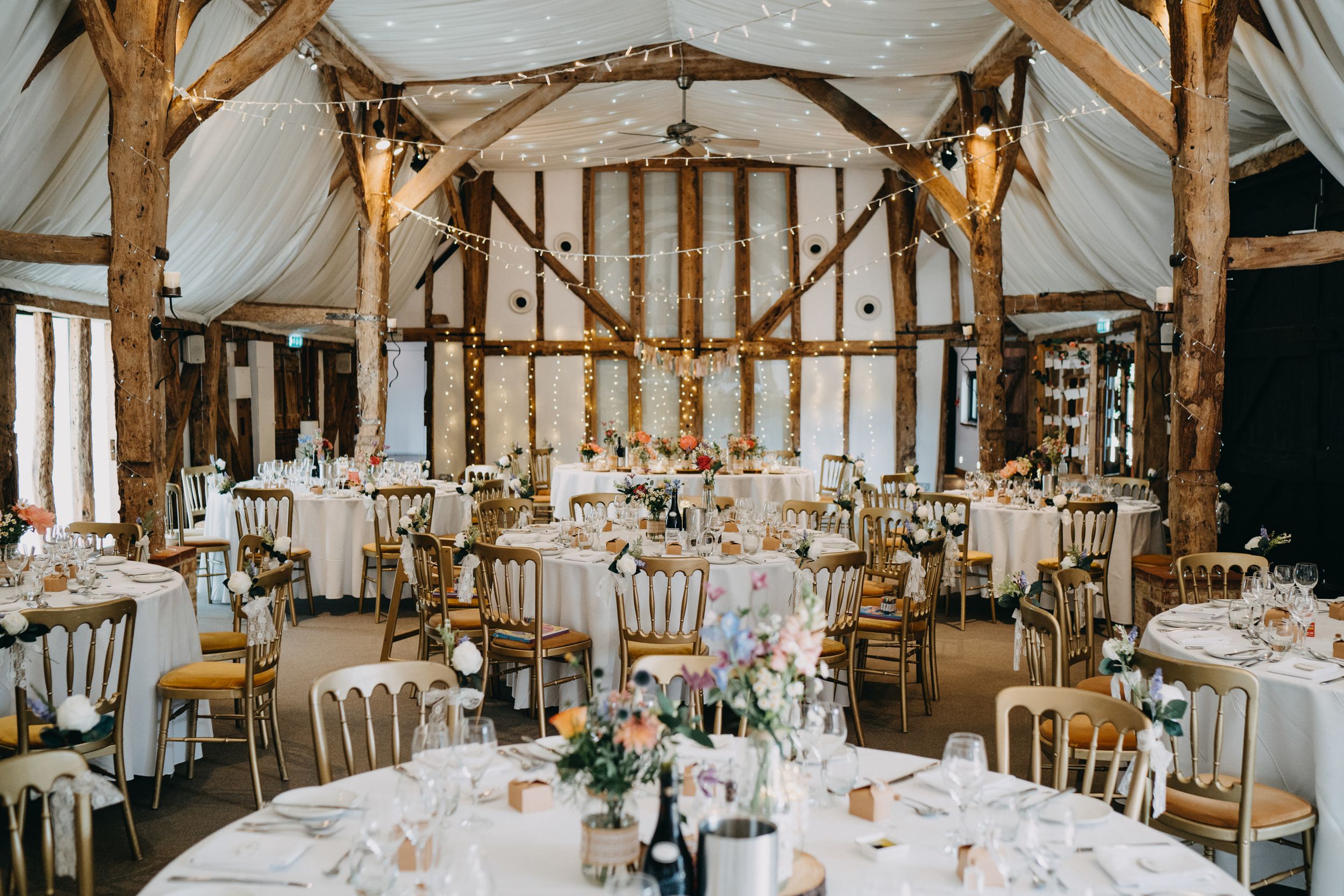 Rustic barn wedding at South Farm reception venue with wooden beams, fairy lights and elegant table settings.