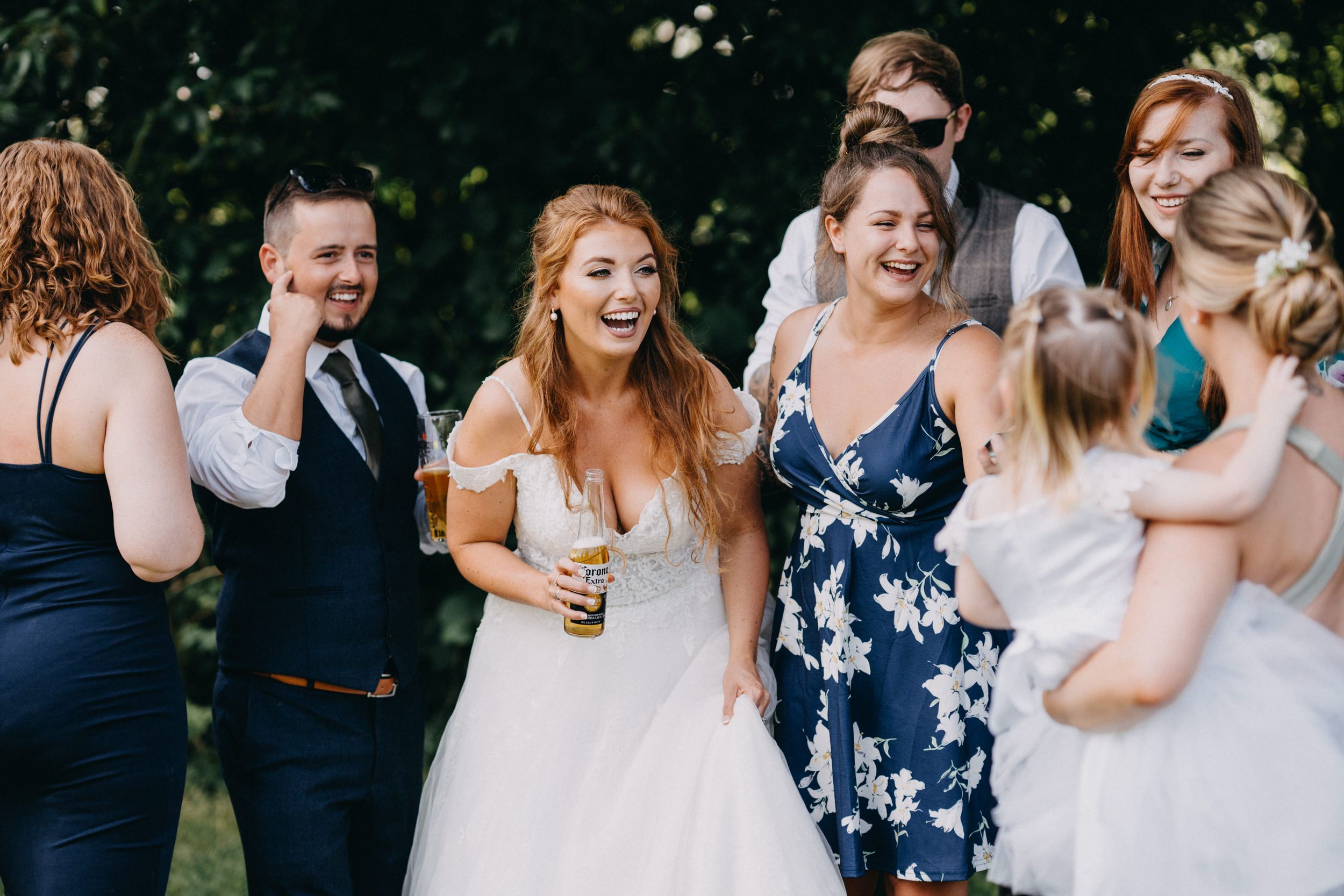 A joyful group enjoying candid laughter during outdoor wedding festivities.