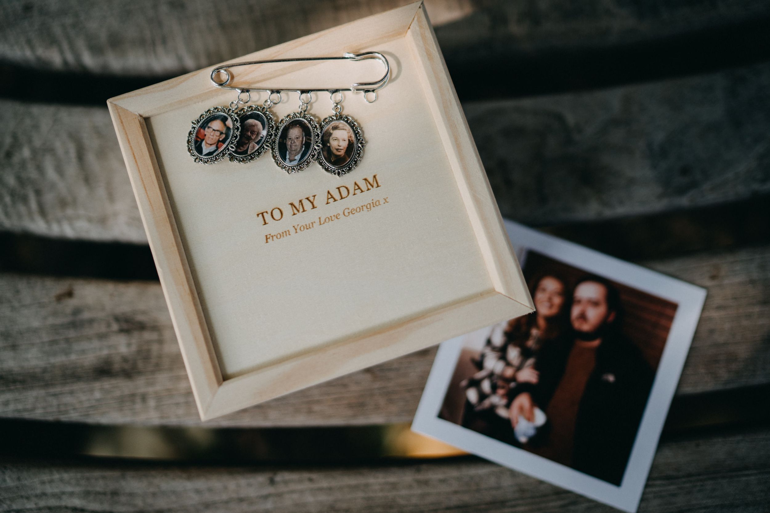 Vintage safety pin with charms and photo displayed on wooden surface.