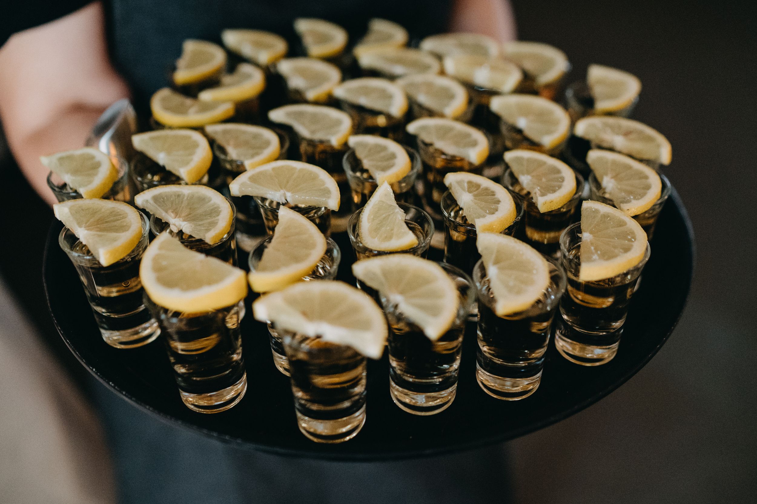 Elegant display of dessert shots garnished with lemon slices arranged on black serving tray.
