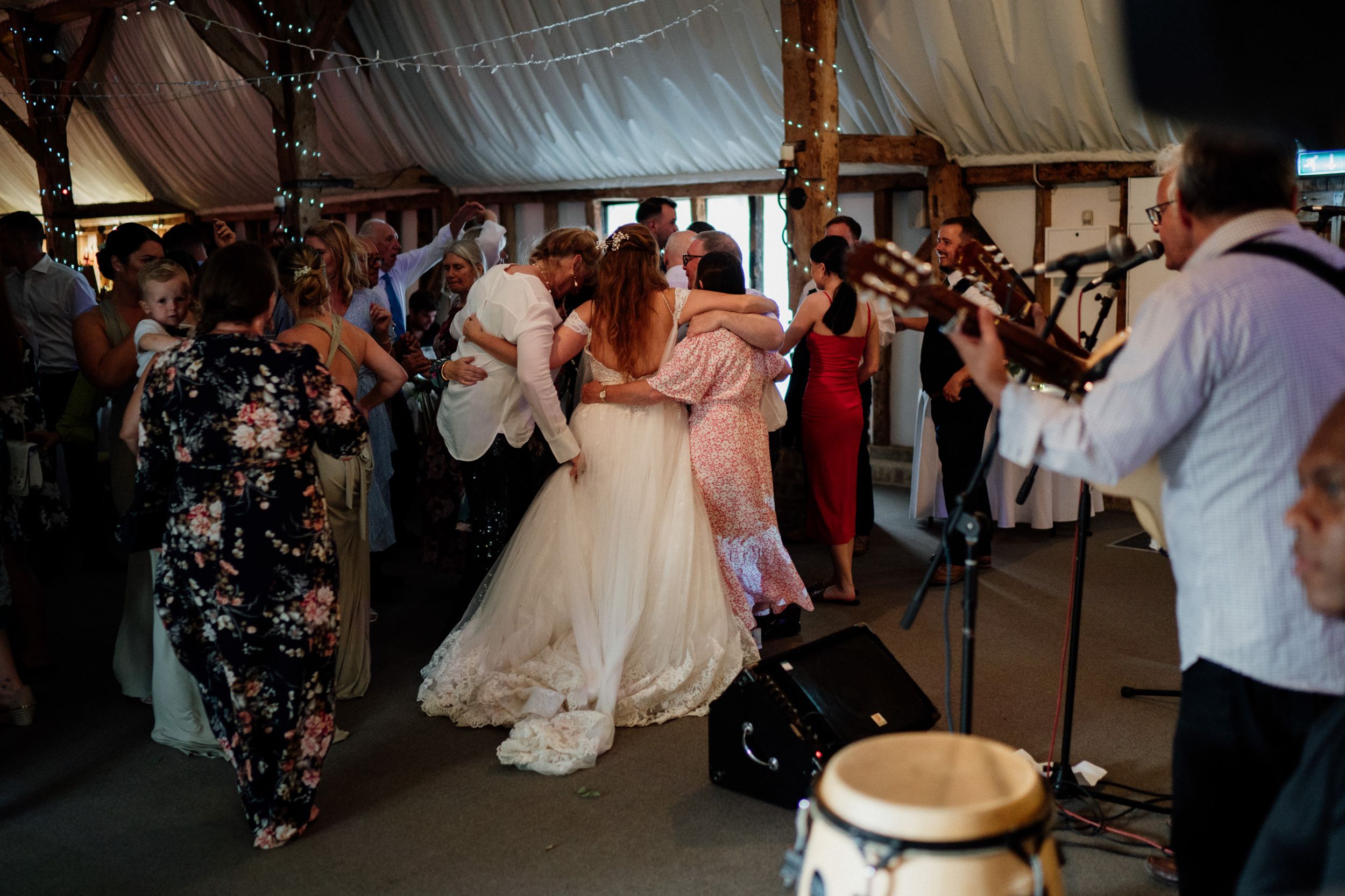 Wedding reception dance party scene under tent with crowd of guests celebrating.