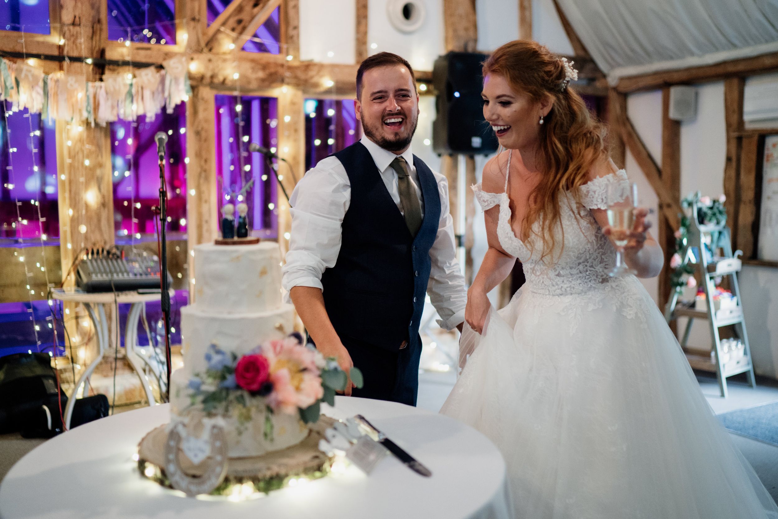 Wedding couple reacts with excitement near their decorated wedding cake at reception.