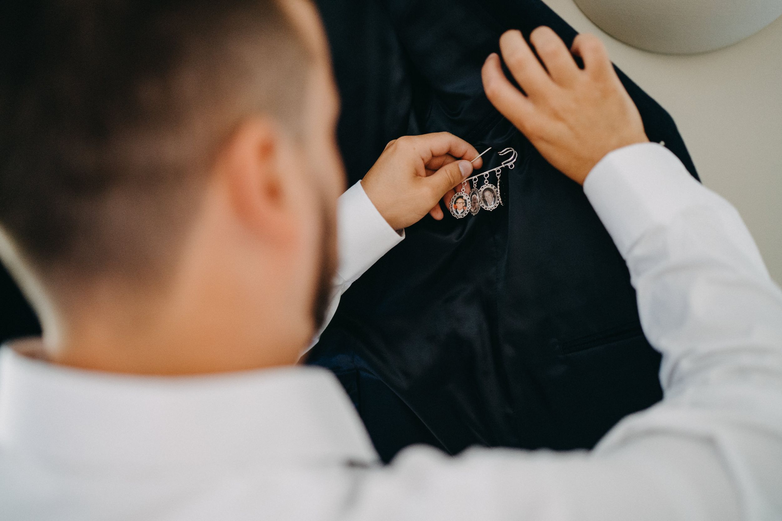Close-up of someone adjusting buttons on a dark formal suit jacket.