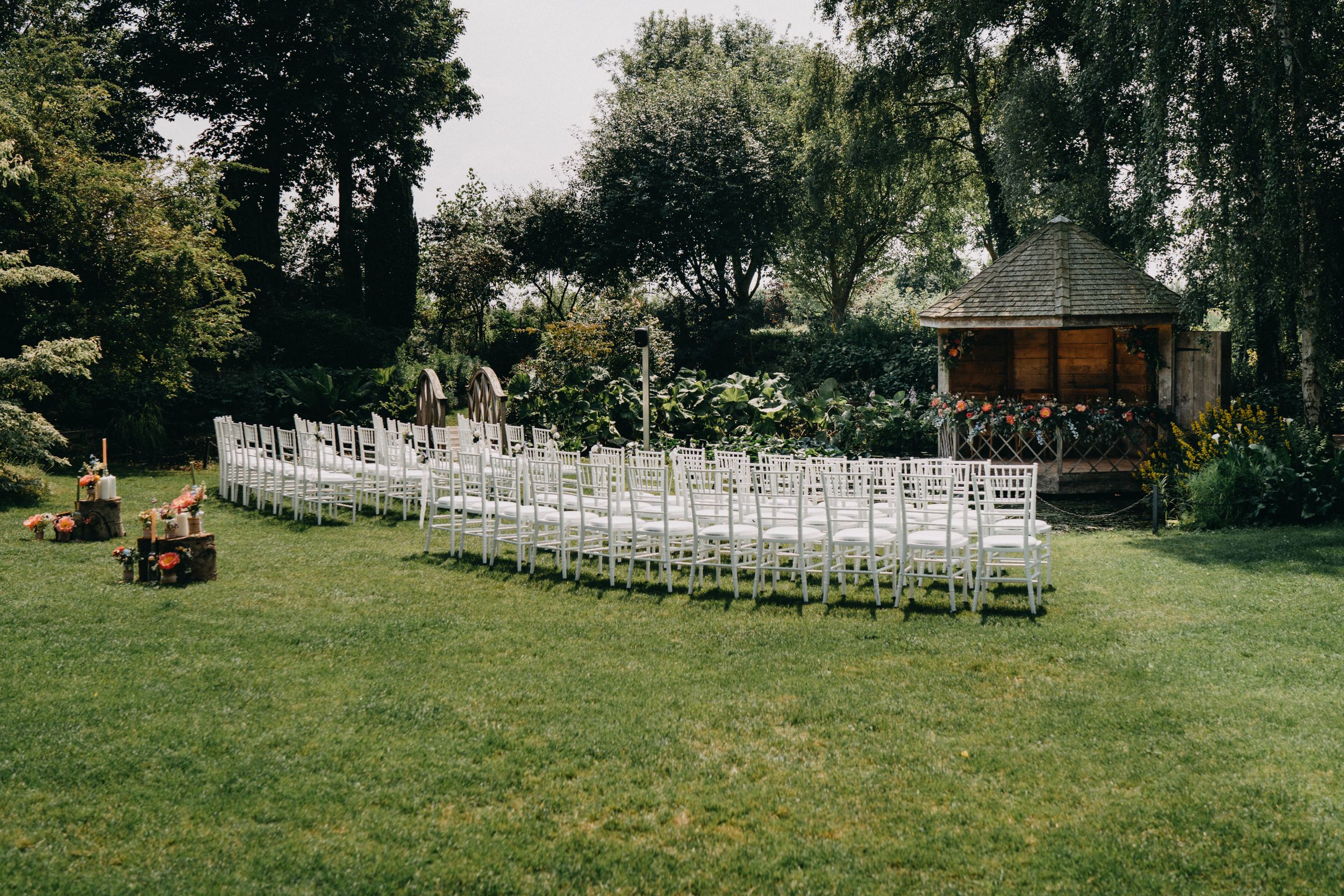 White chairs arranged in curved rows on a lush garden lawn for an outdoor wedding ceremony at South Farm.