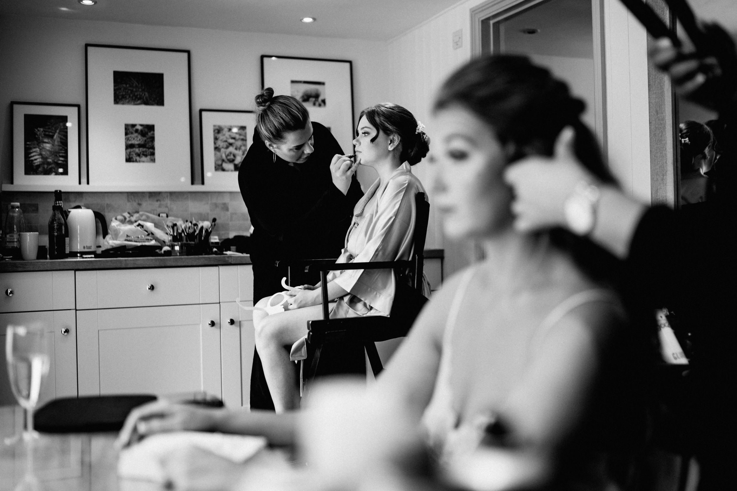 Black and white photo of wedding preparation activities in a kitchen setting.