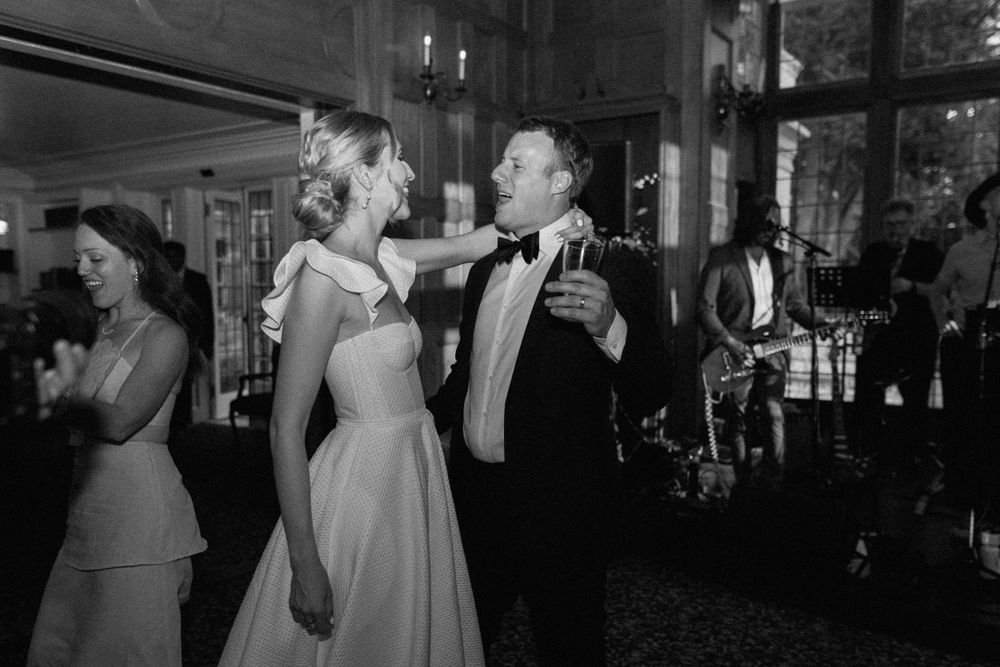 A bride and groom share a joyful moment on the dance floor during their black and white wedding reception.