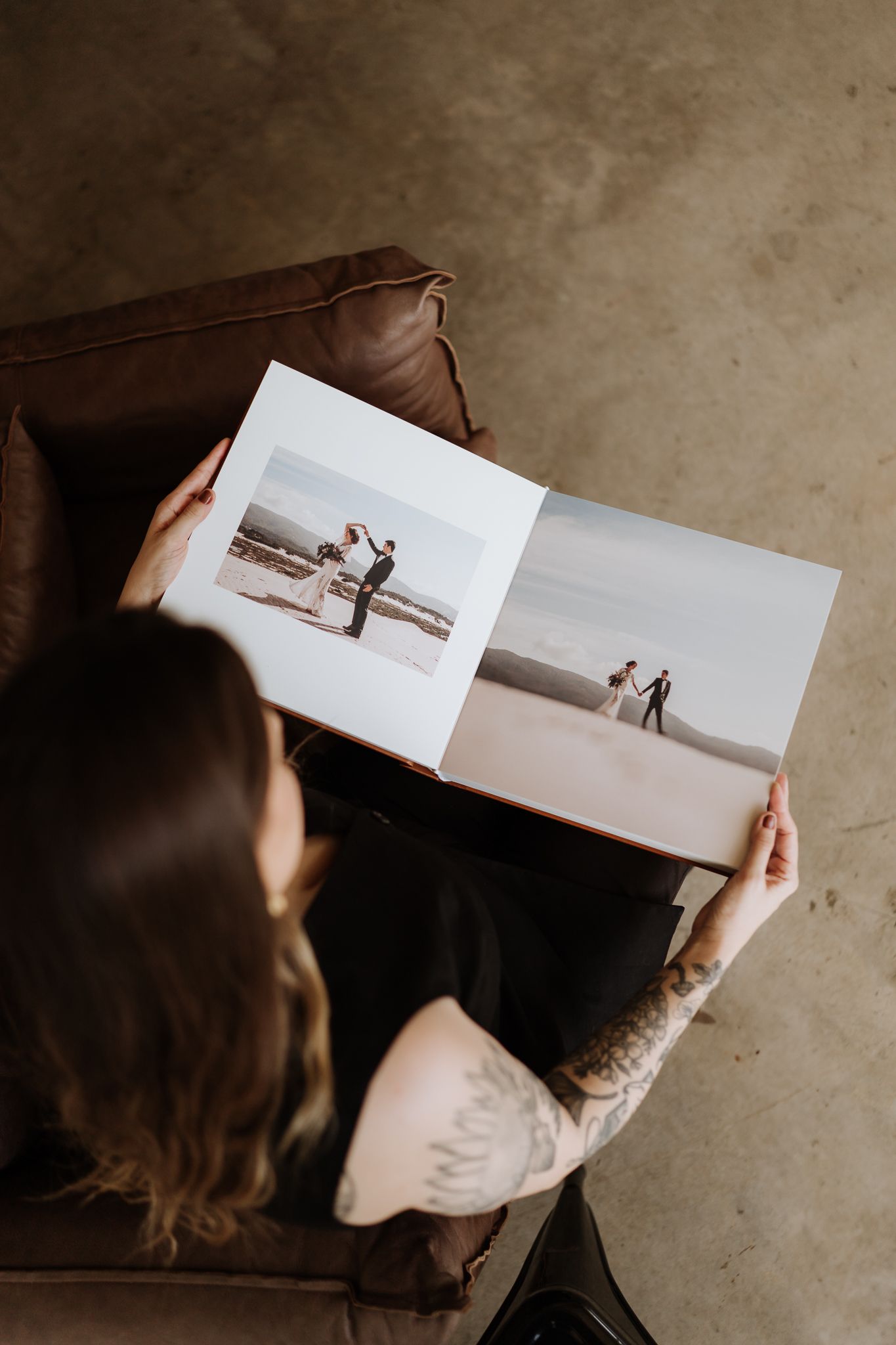 Person viewing wedding photo album featuring beach ceremony pictures.
