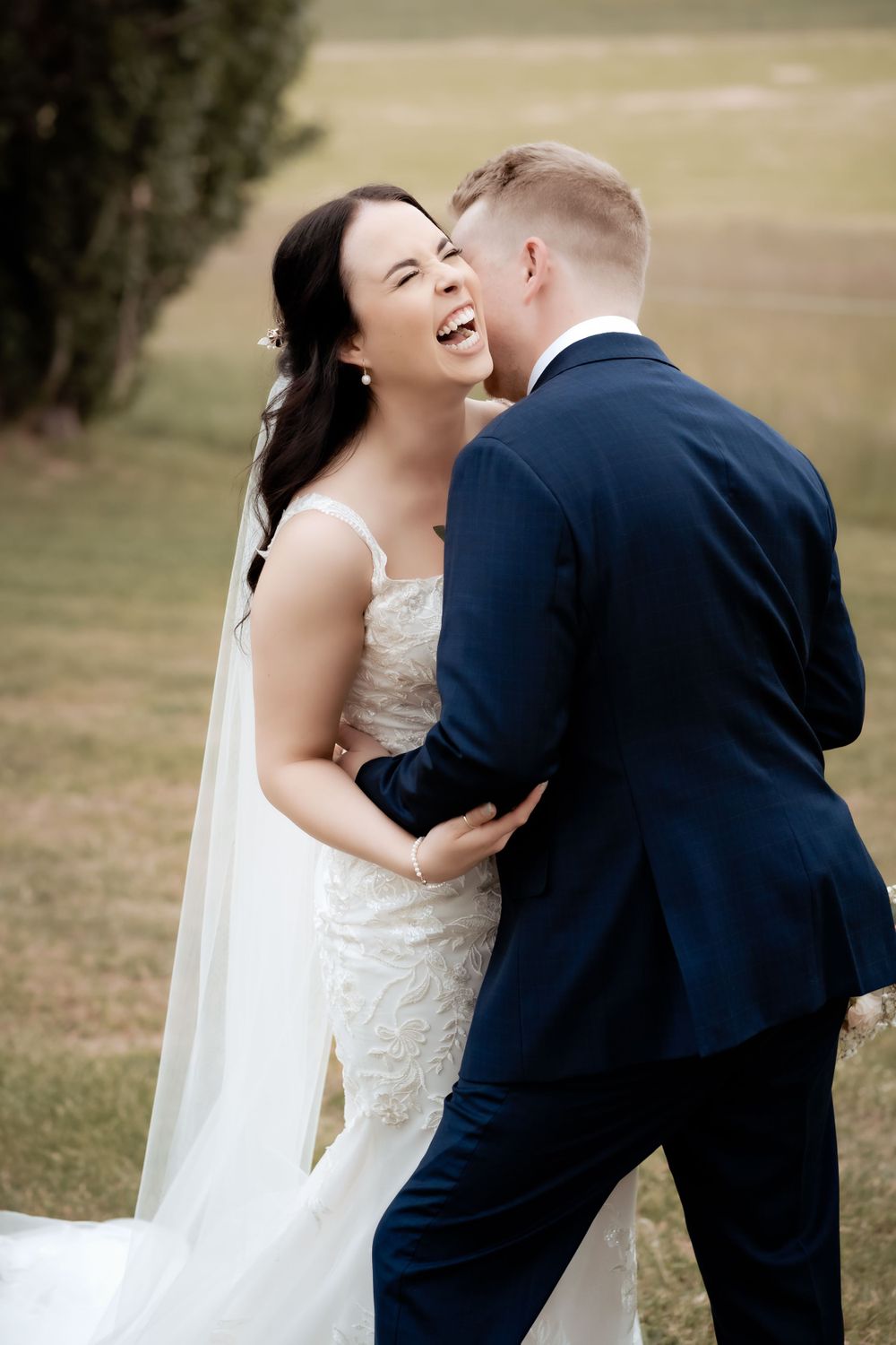 A joyful wedding moment captured outdoors with flowing veil.