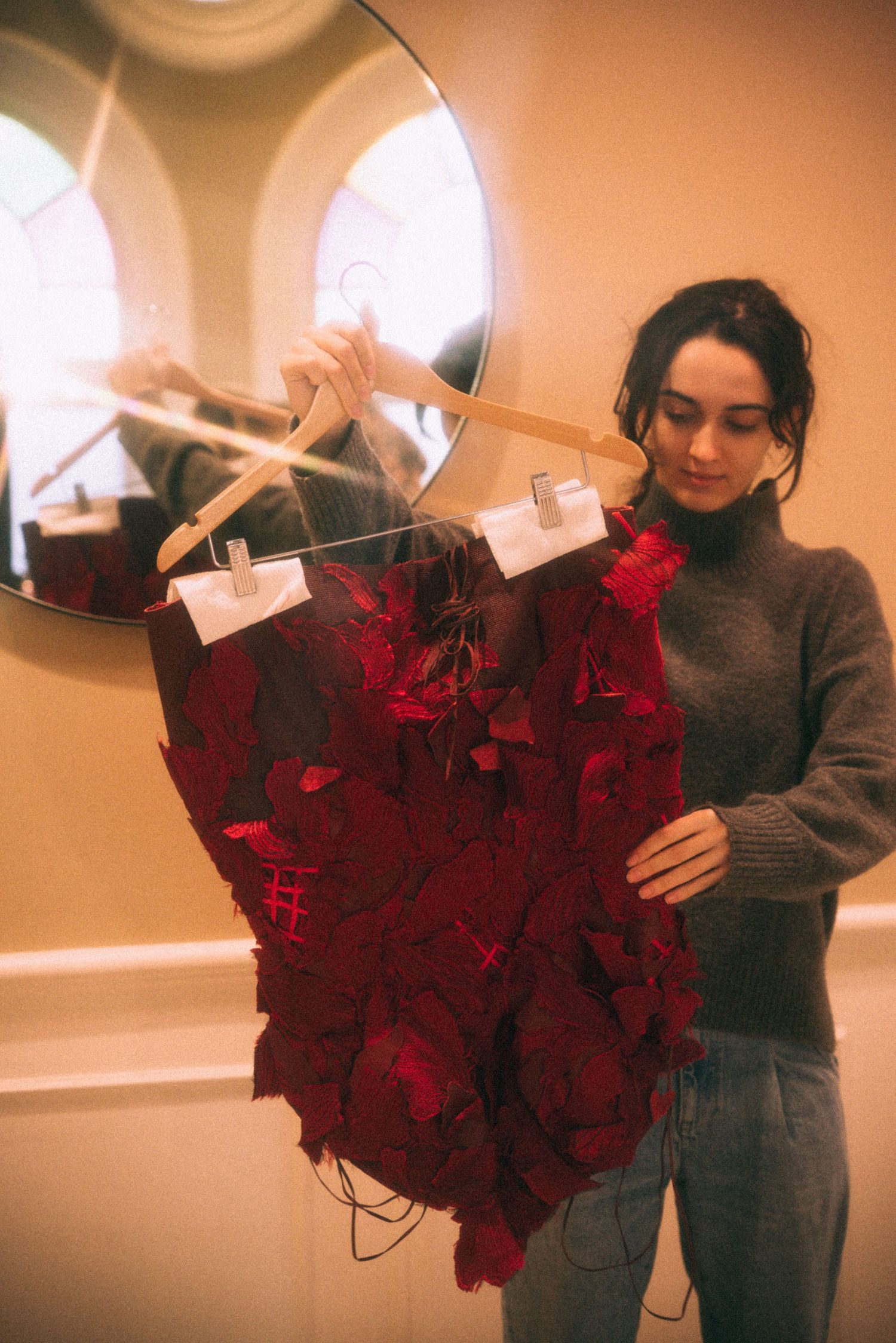 Fashion designer holding heart-shaped red rose arrangement against mirror in romantic setting in a editorial photoshoot