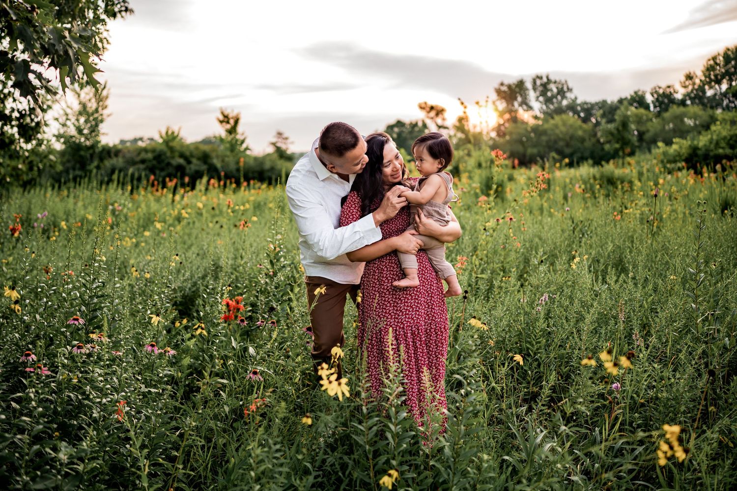 A loving embrace shared in a meadow filled with yellow wildflowers at sunset.