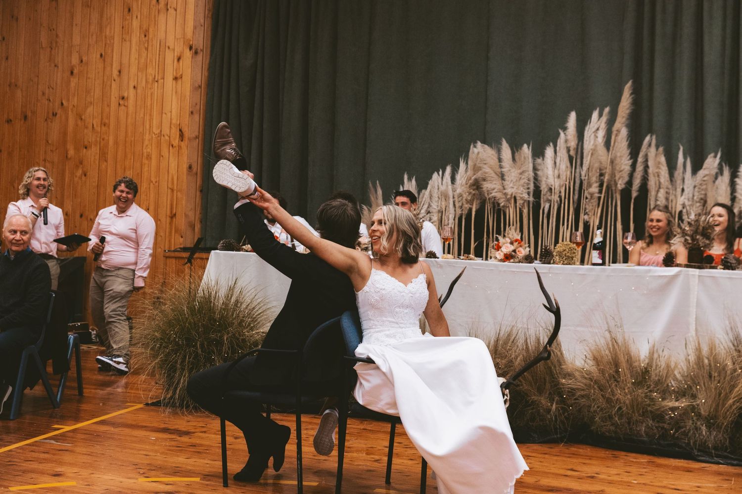 Wedding couple performs playful dip dance move in front of reception head table.