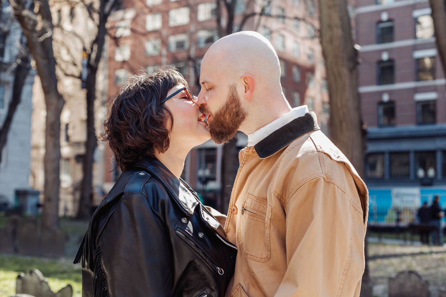 A tender moment shared between a couple in front of urban architecture.