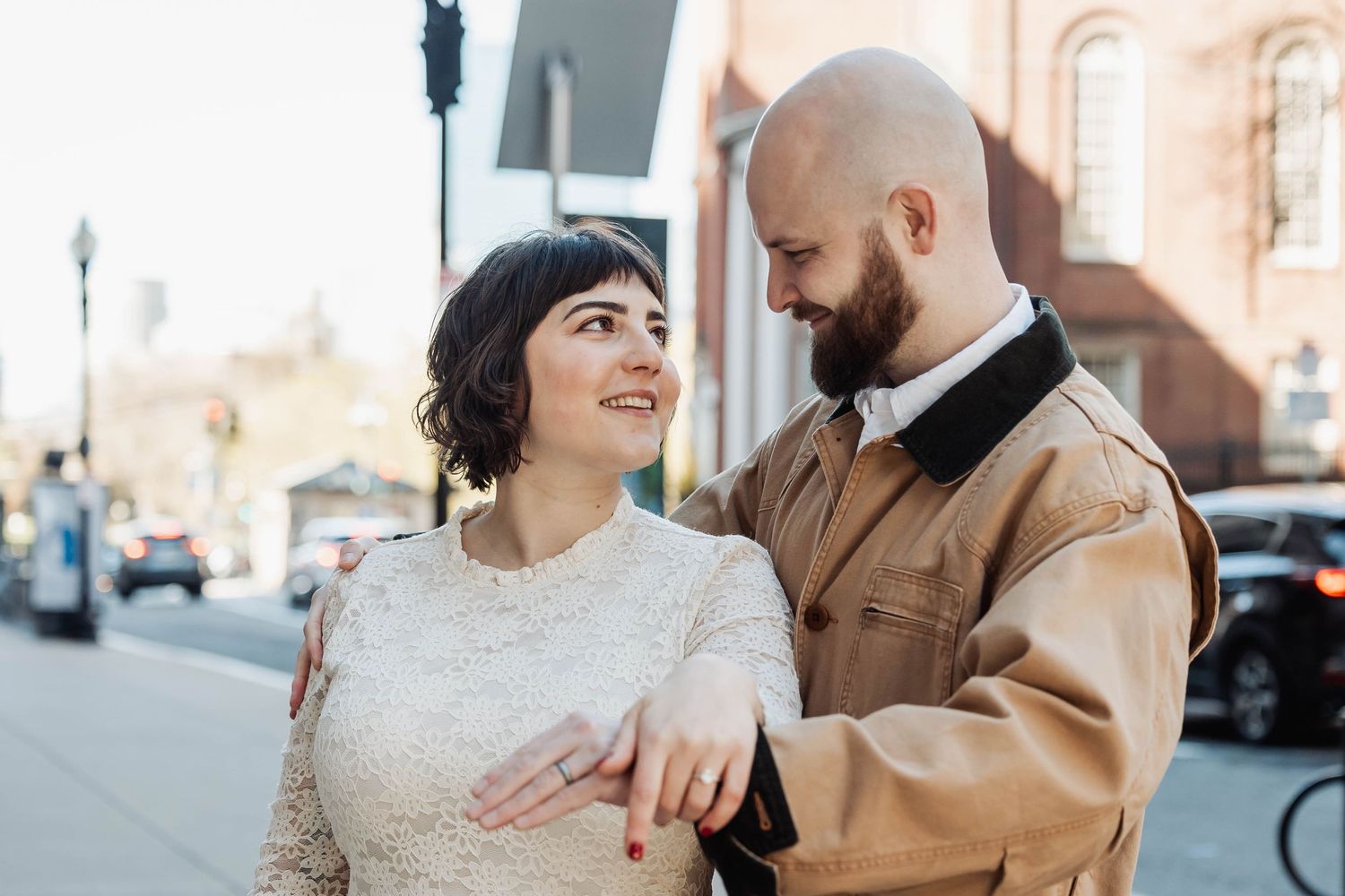 A couple shares a joyful moment on a city sidewalk.