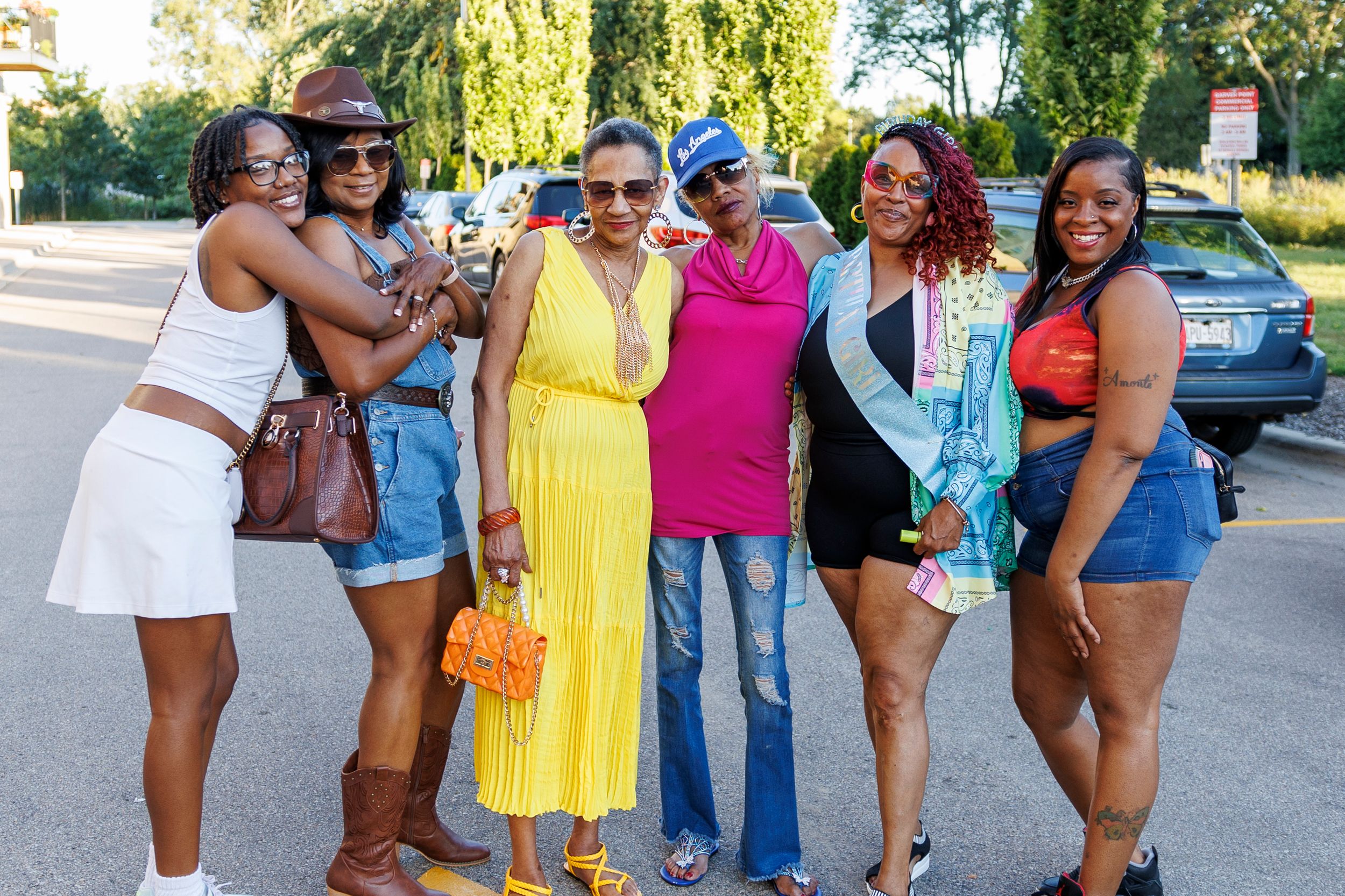 Group of friends posing together outdoors wearing summer outfits and colorful attire.