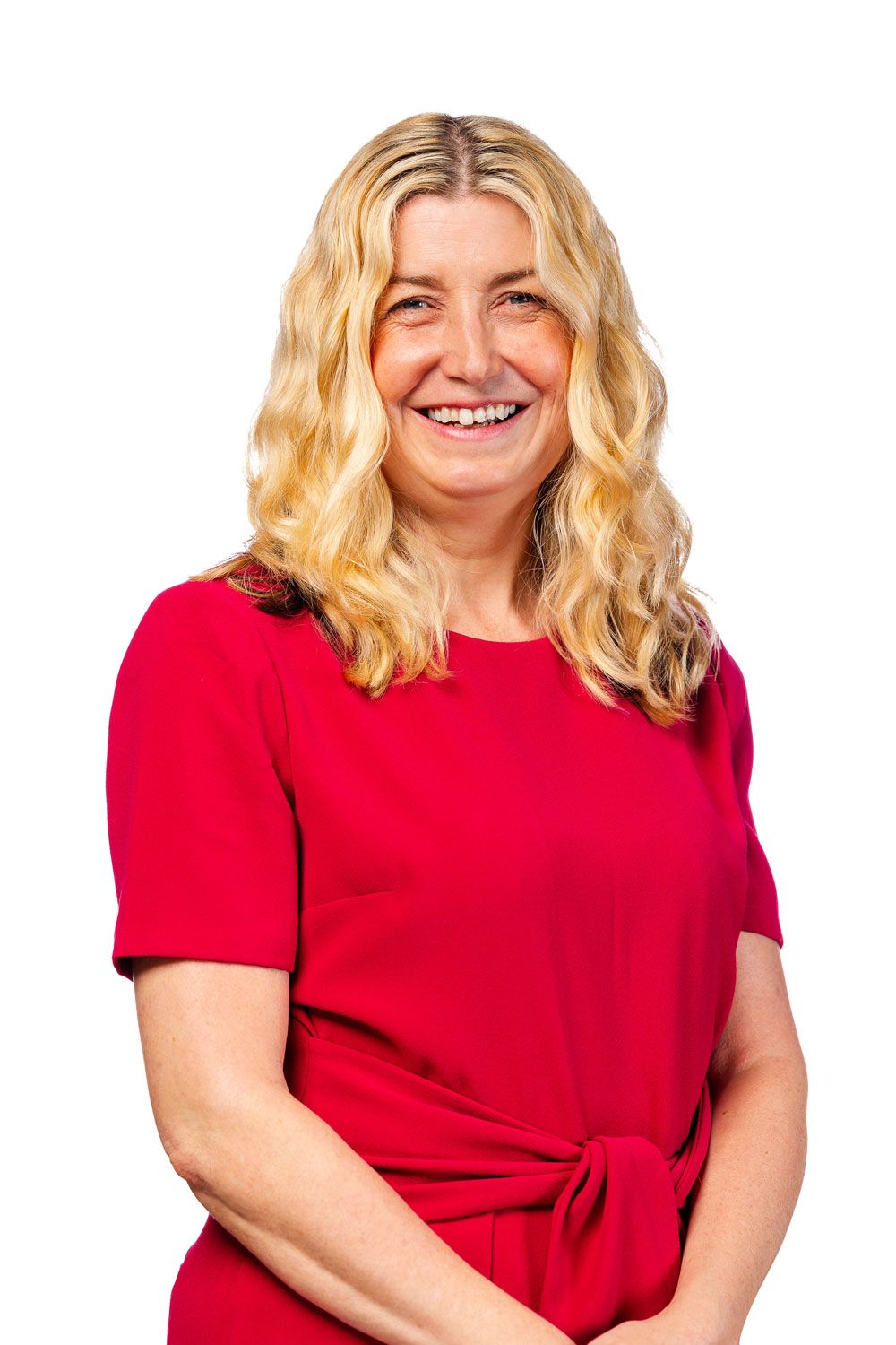 Smiling woman with shoulder-length blonde hair, wearing red dress with short sleeves.