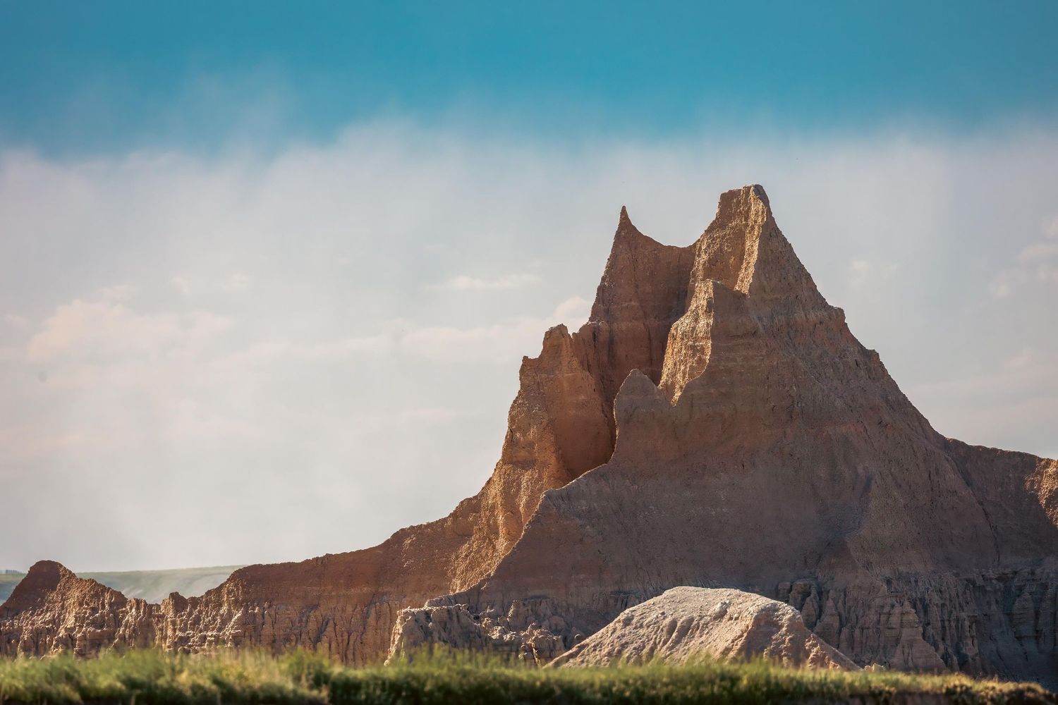 Dramatic rock formation in Badlands National Park against bright blue sky.