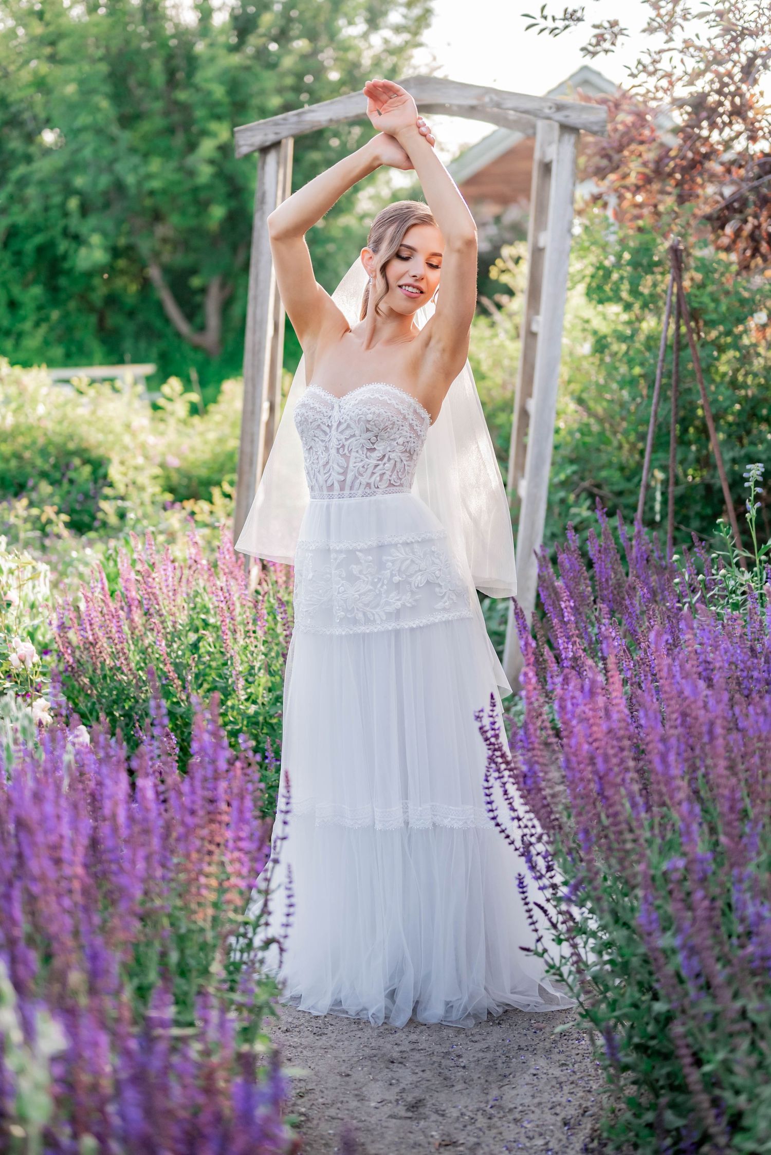 Bride twirls in white wedding gown surrounded by blooming purple lavender flowers.