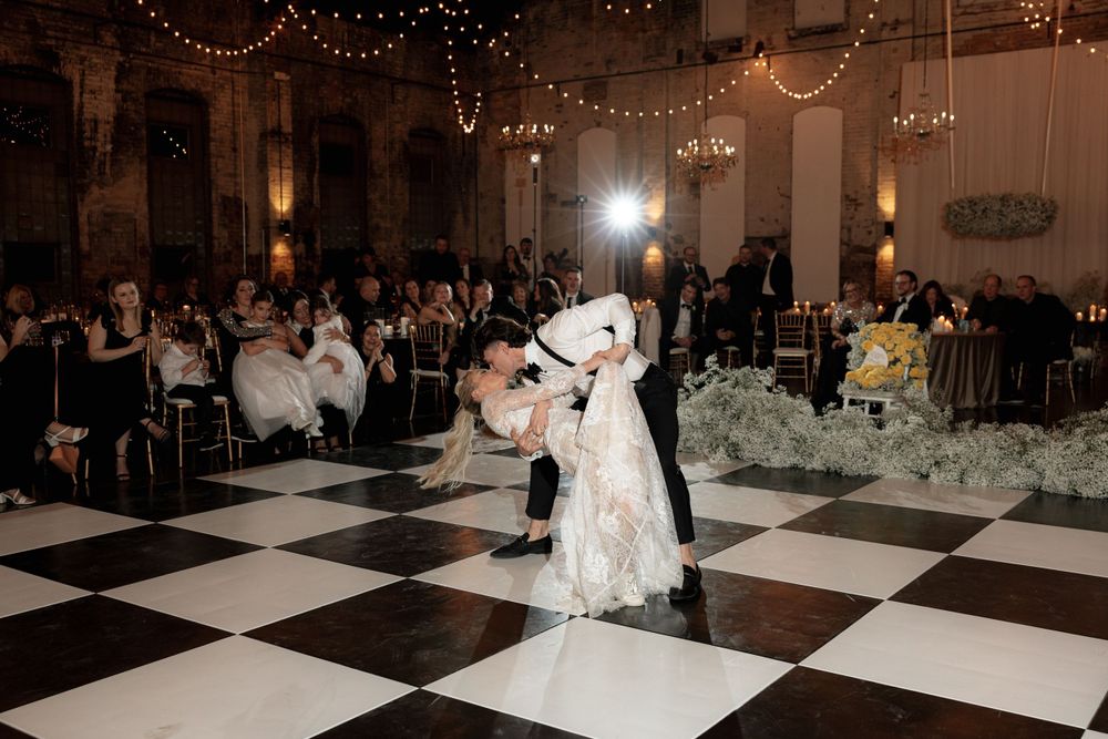 A romantic dip during a wedding dance under sparkling chandeliers and string lights.