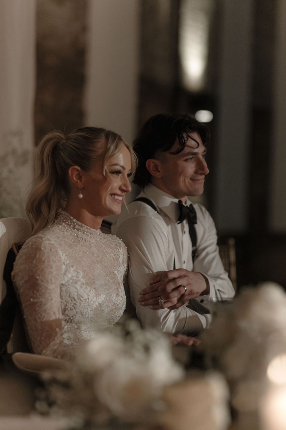 Couple sharing a joyful moment at their wedding reception with soft candlelight.