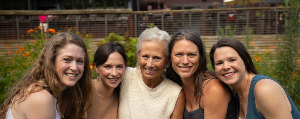 A happy group smiles together during an outdoor photo session in a garden setting.