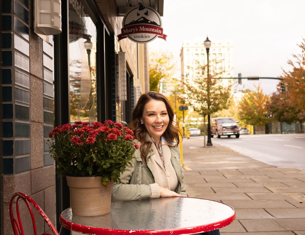 Cafe scene with outdoor seating featuring red table and autumn floral arrangements on a city sidewalk.