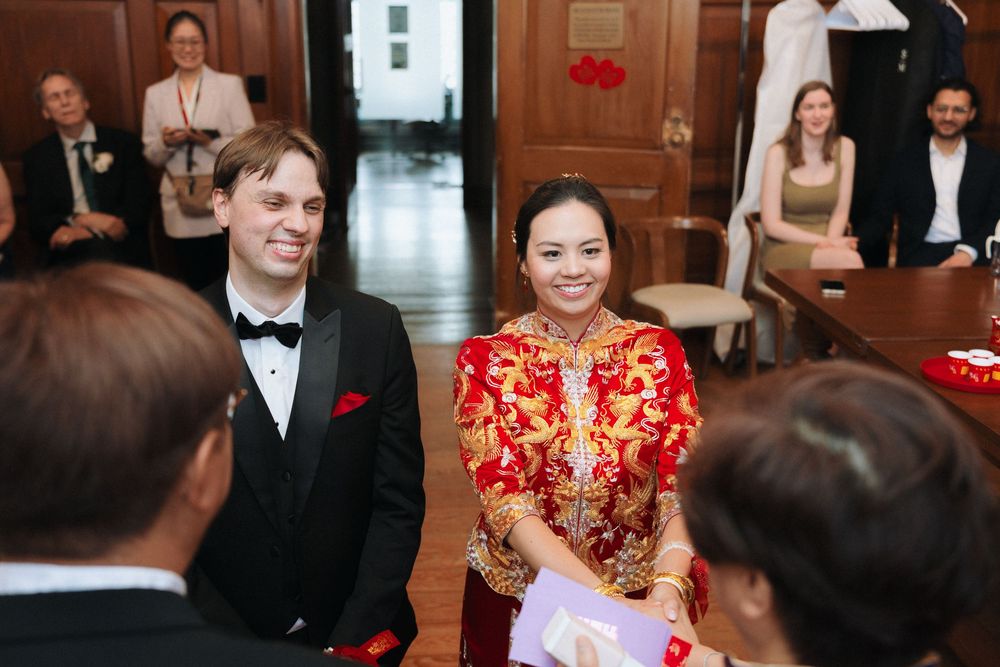 Wedding guests celebrate and interact during a reception in an elegant venue with wooden details.