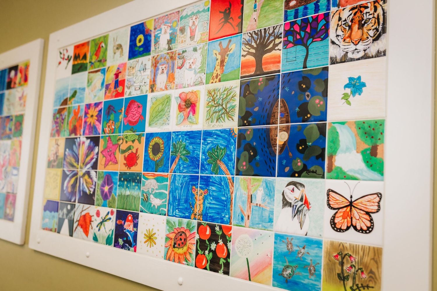 A colorful collage wall display of children's artwork featuring butterflies, animals, and nature-themed paintings in various styles.