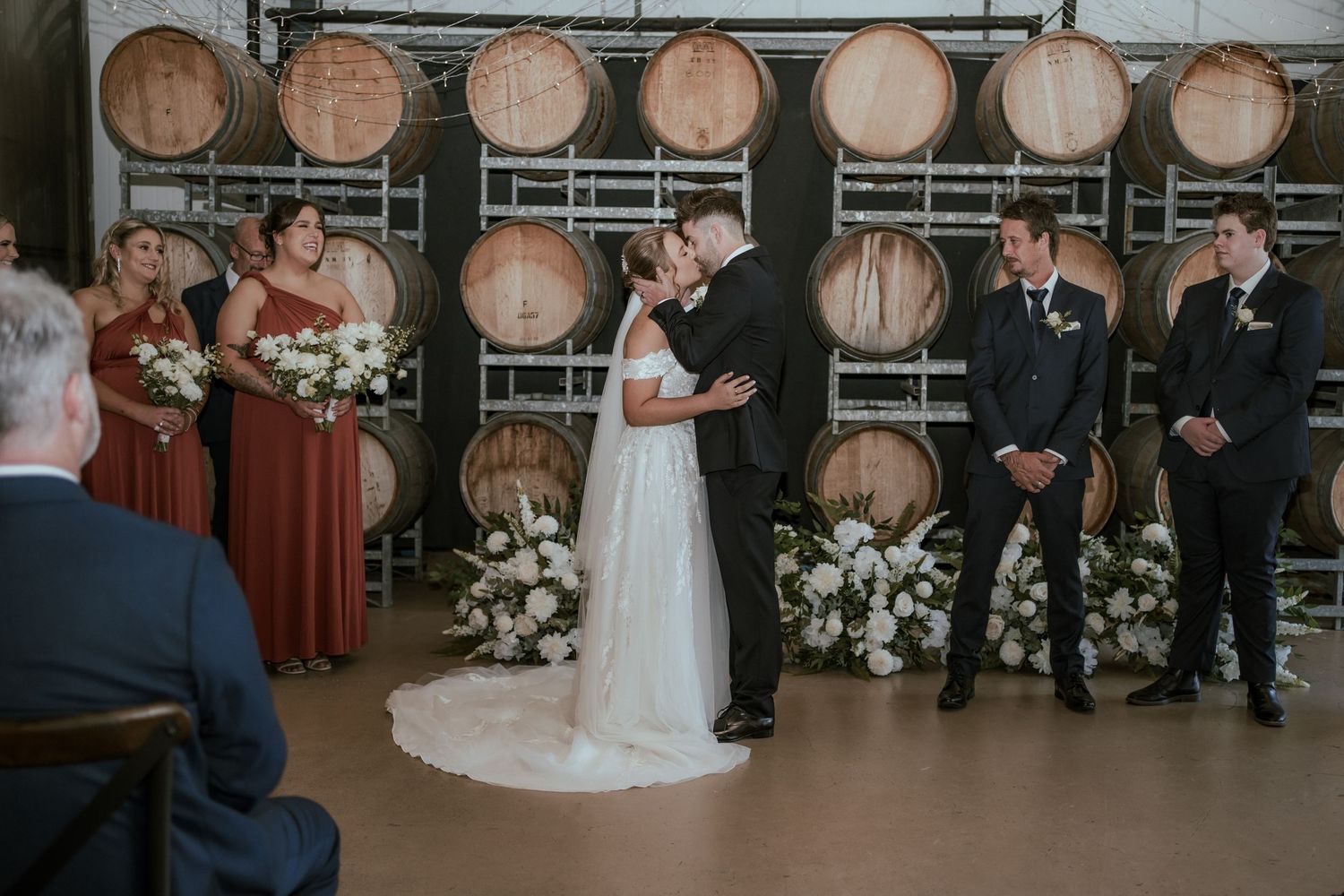 A wedding ceremony in a rustic winery barrel room with wooden decor.