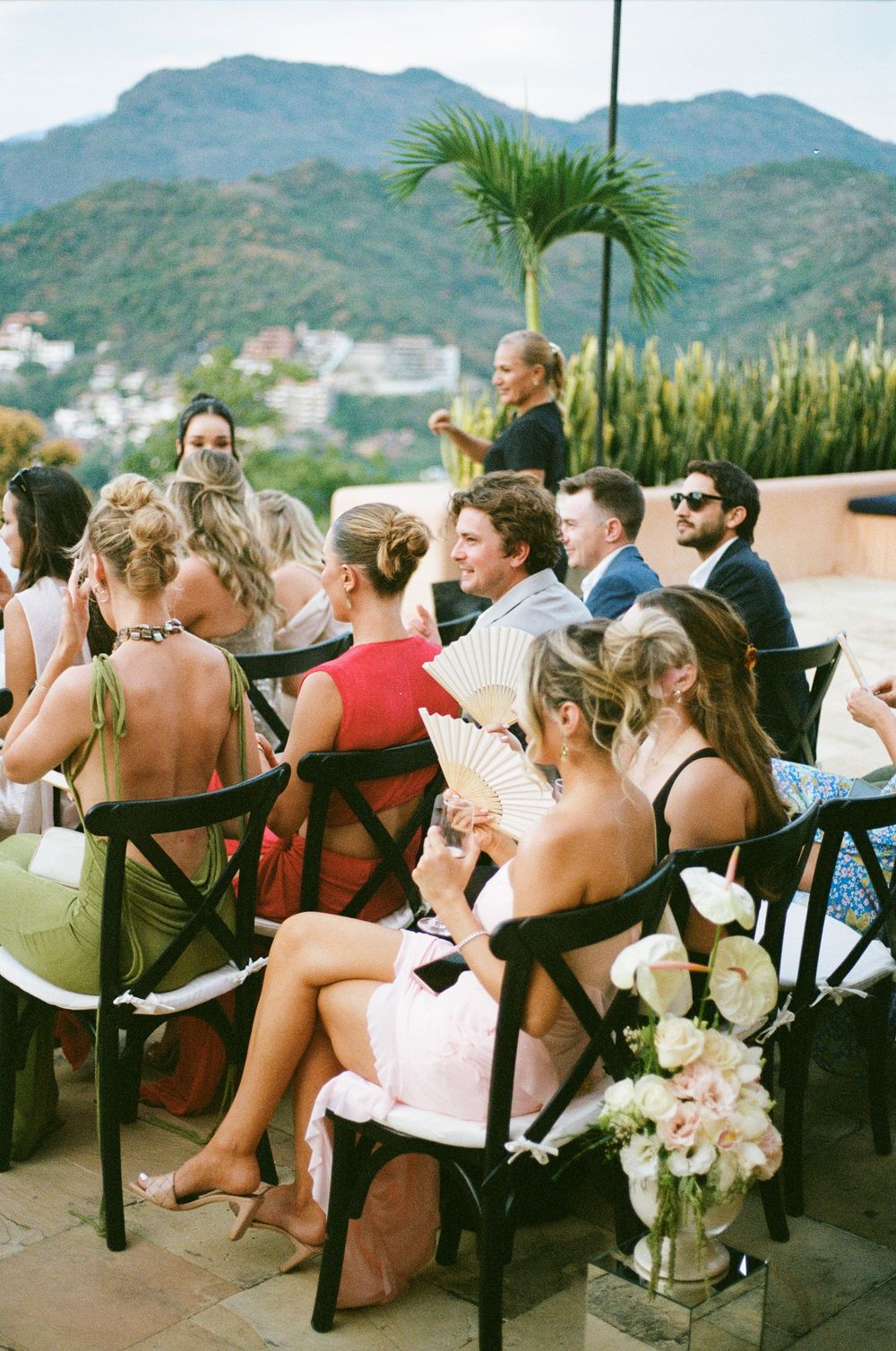 Guests enjoying an outdoor wedding reception with mountain views and a palm tree in the background.