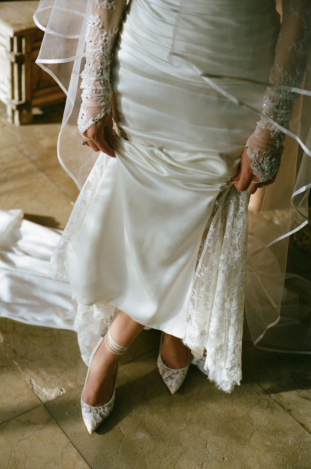 Close-up of lace wedding dress details and embellished bridal shoes.