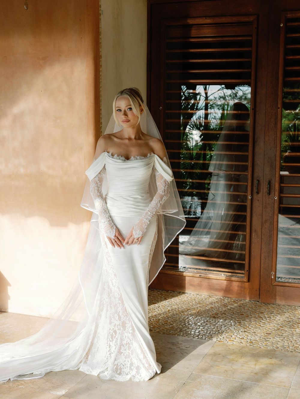 Elegant wedding dress with off-shoulder design photographed in natural light.