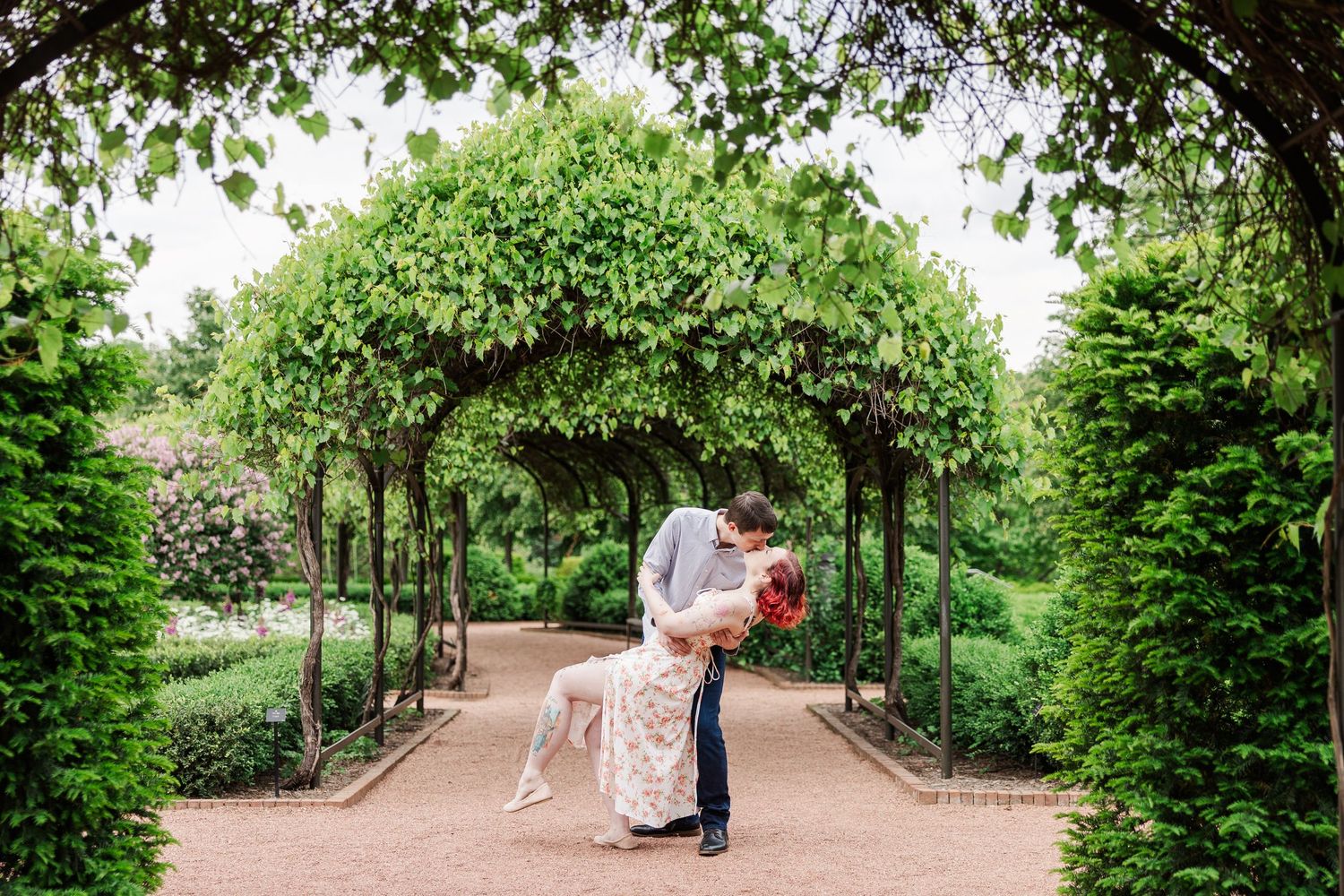 A romantic moment under an arched garden trellis covered in lush green vines and foliage in a formal garden setting.at Cantigny Park