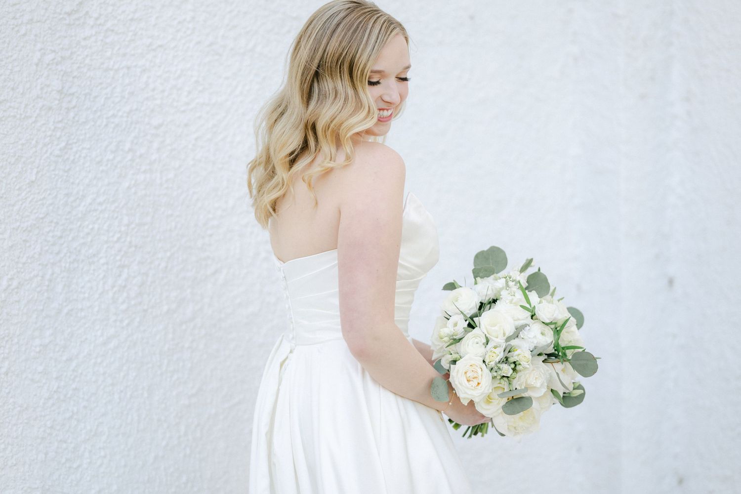 Bridal party in elegant black dresses and white bouquets poses together on mansion steps.