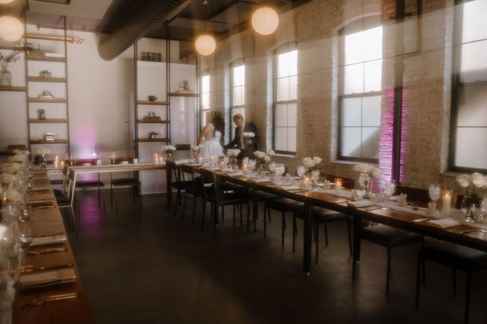 Elegant dining room setup with long tables, wooden shelving, and pendant lights creating a warm ambiance.