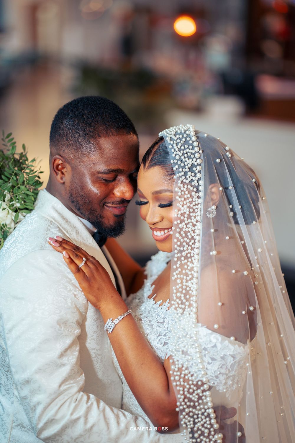 A romantic wedding moment between newlyweds embracing, with the bride wearing an elegant beaded veil and dress.