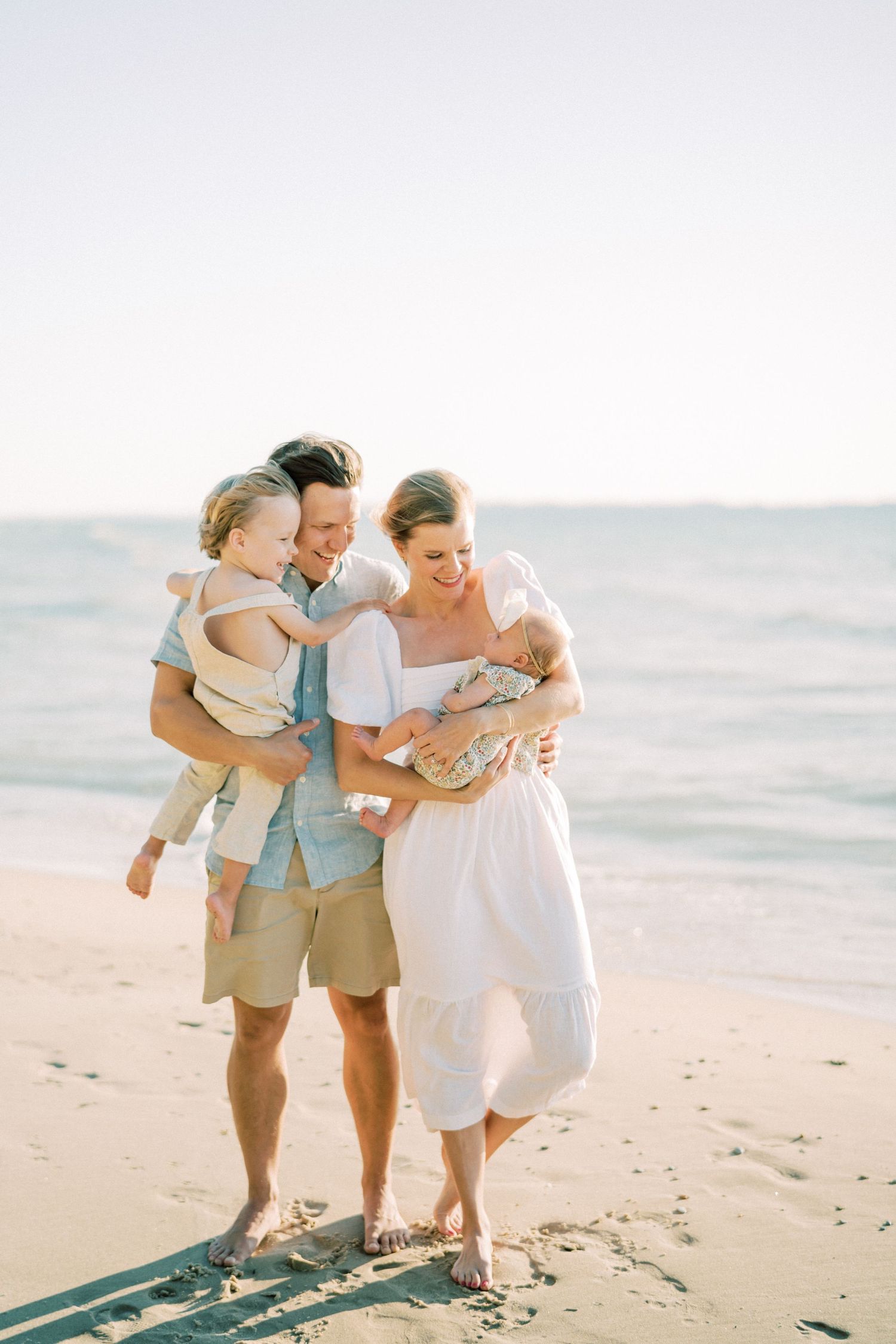 Family walking together on sunny beach in casual summer clothing.