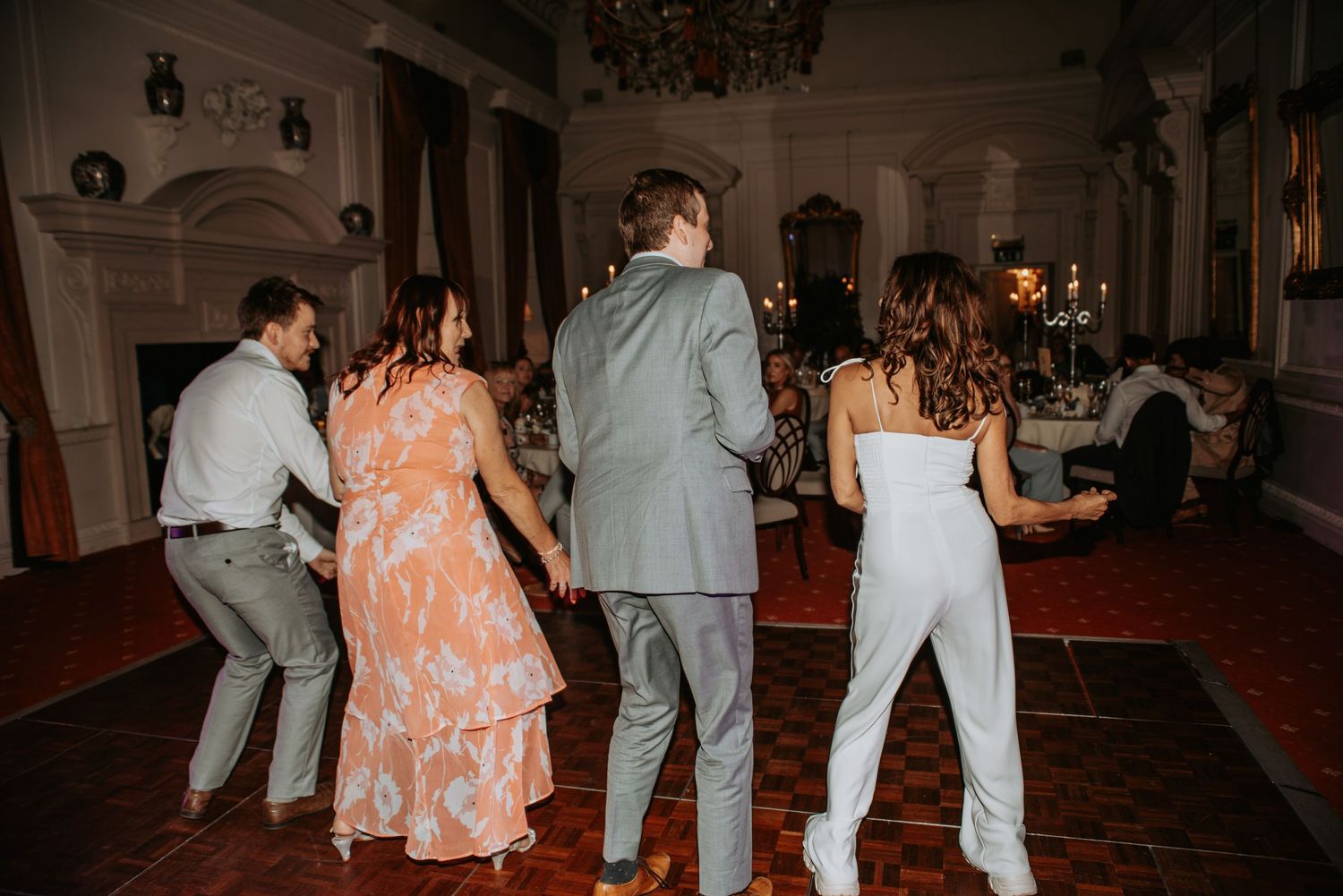 Wedding guests dancing and enjoying themselves on a dimly lit dance floor at an elegant indoor reception venue.