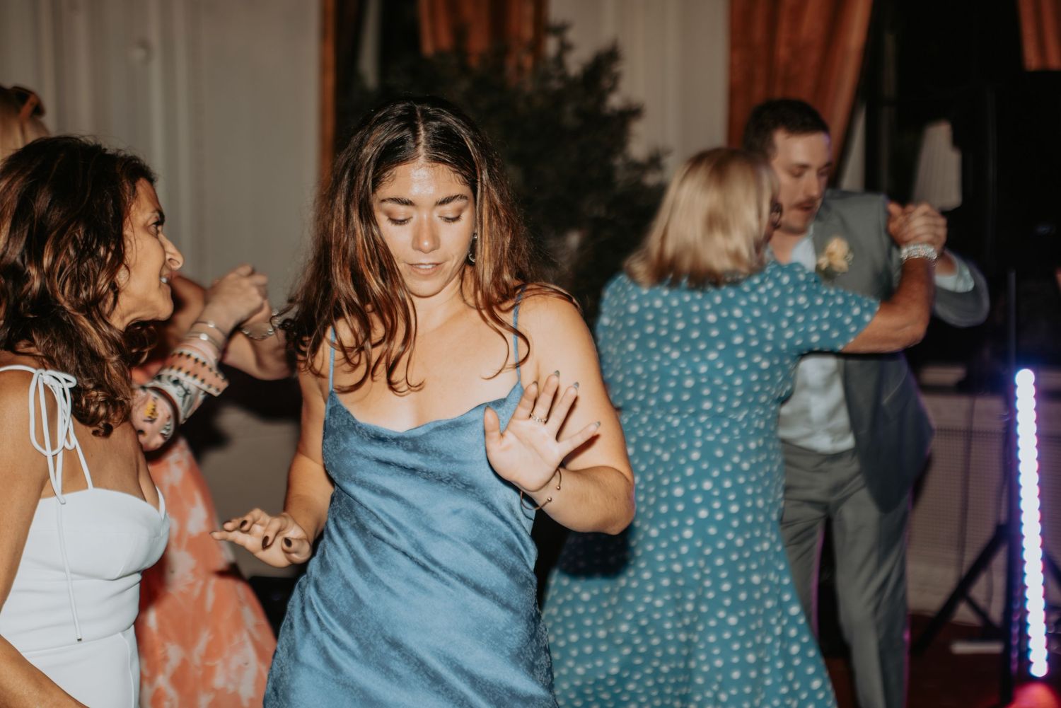 People dancing and having fun at a party with a woman in blue dress in the center of the dance floor.