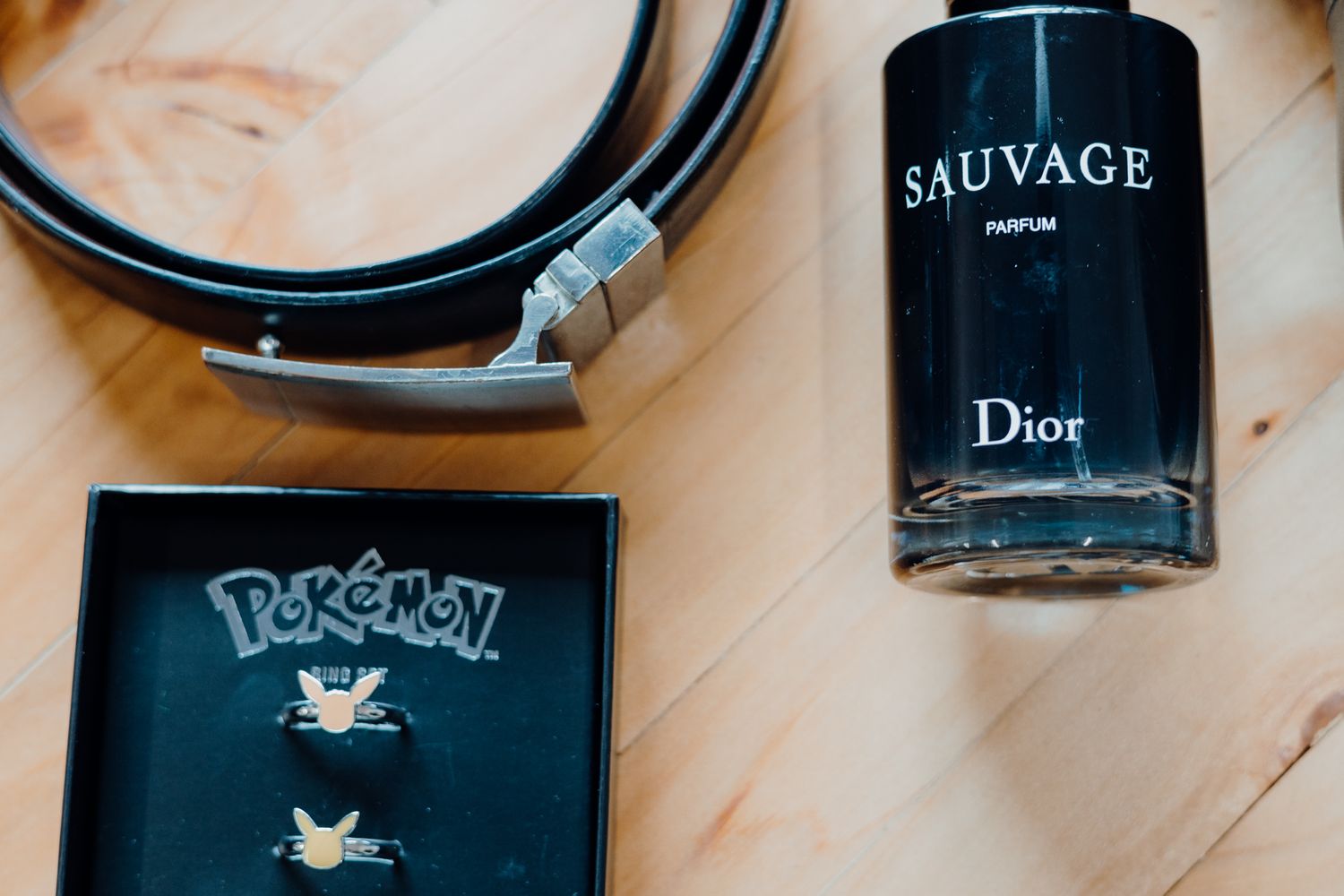 Dior Sauvage perfume bottle and Pokemon card displayed on wooden surface.