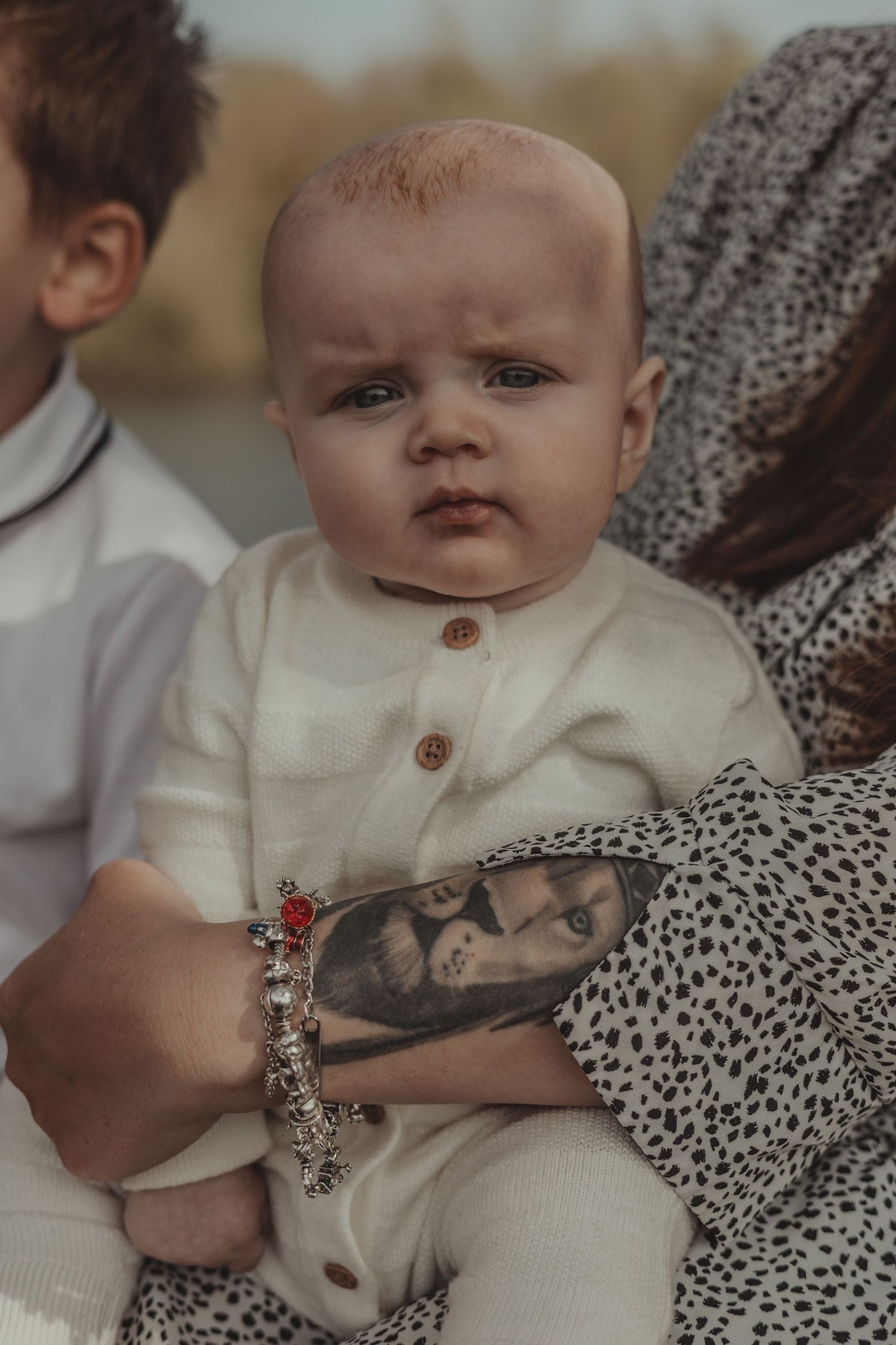 family session, close up of baby in mums tattooed arms, colour, grain
