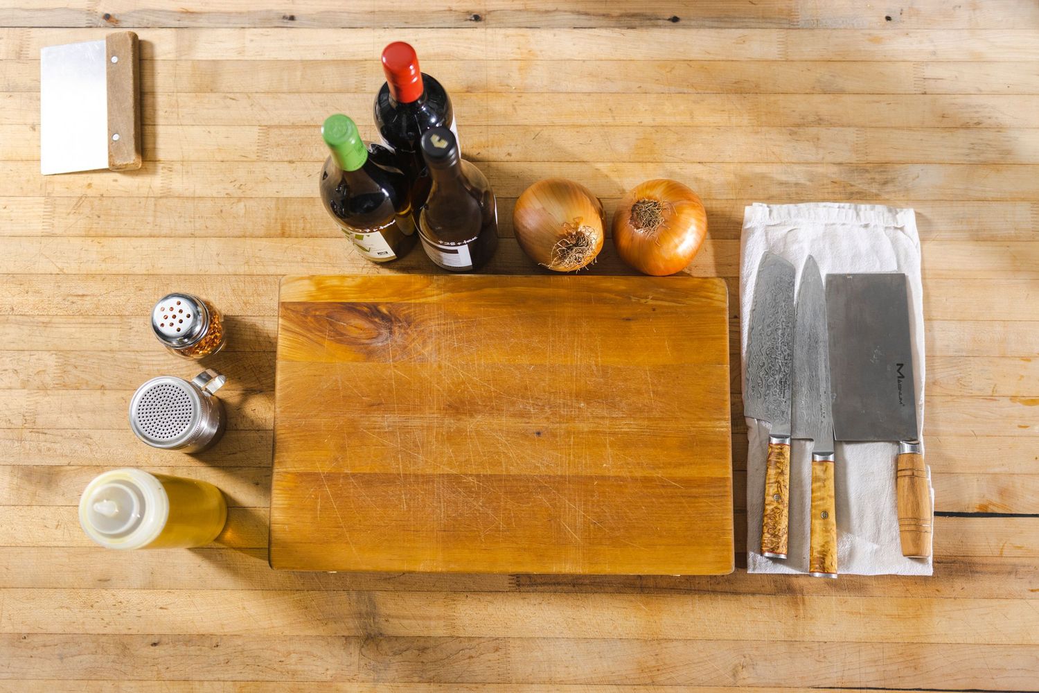 Top-down view of wooden cutting board with cooking ingredients and seasonings arranged on rustic wooden table.