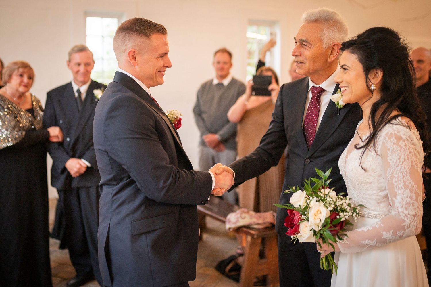 Happy wedding party gathers for a joyful moment during the ceremony as guests watch from behind.